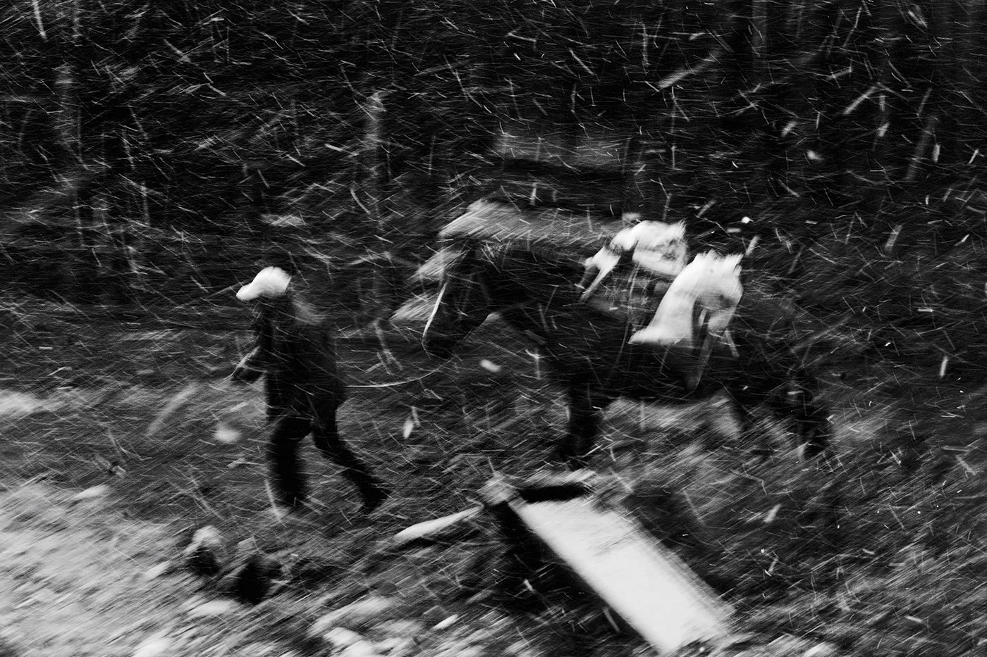 A person walking in a snowstorm at night, with snow falling heavily and obscuring the surroundings.