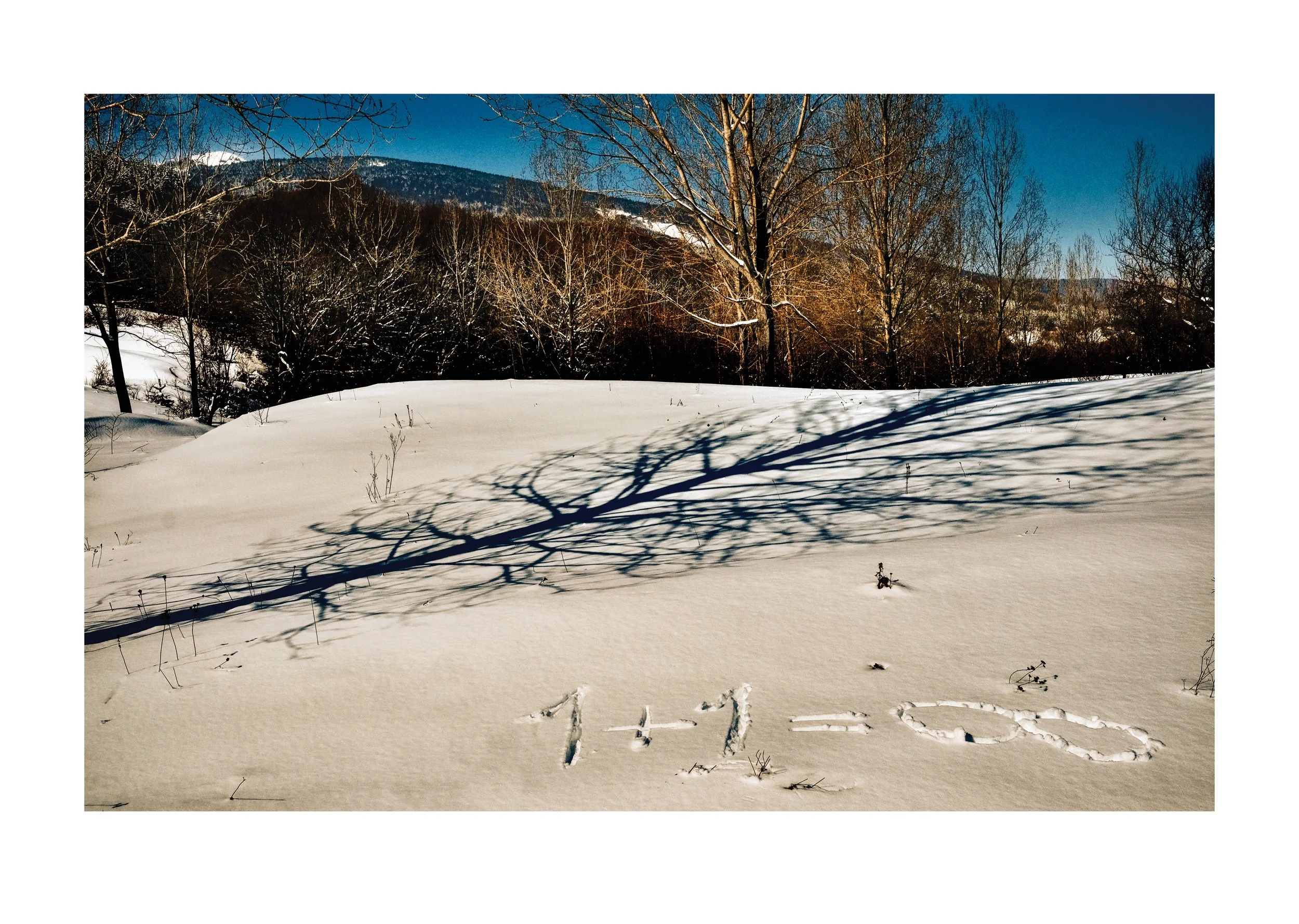 Snow-covered landscape with leafless trees and mountain scenery in the background, and the word 'HELLO' written in the snow.