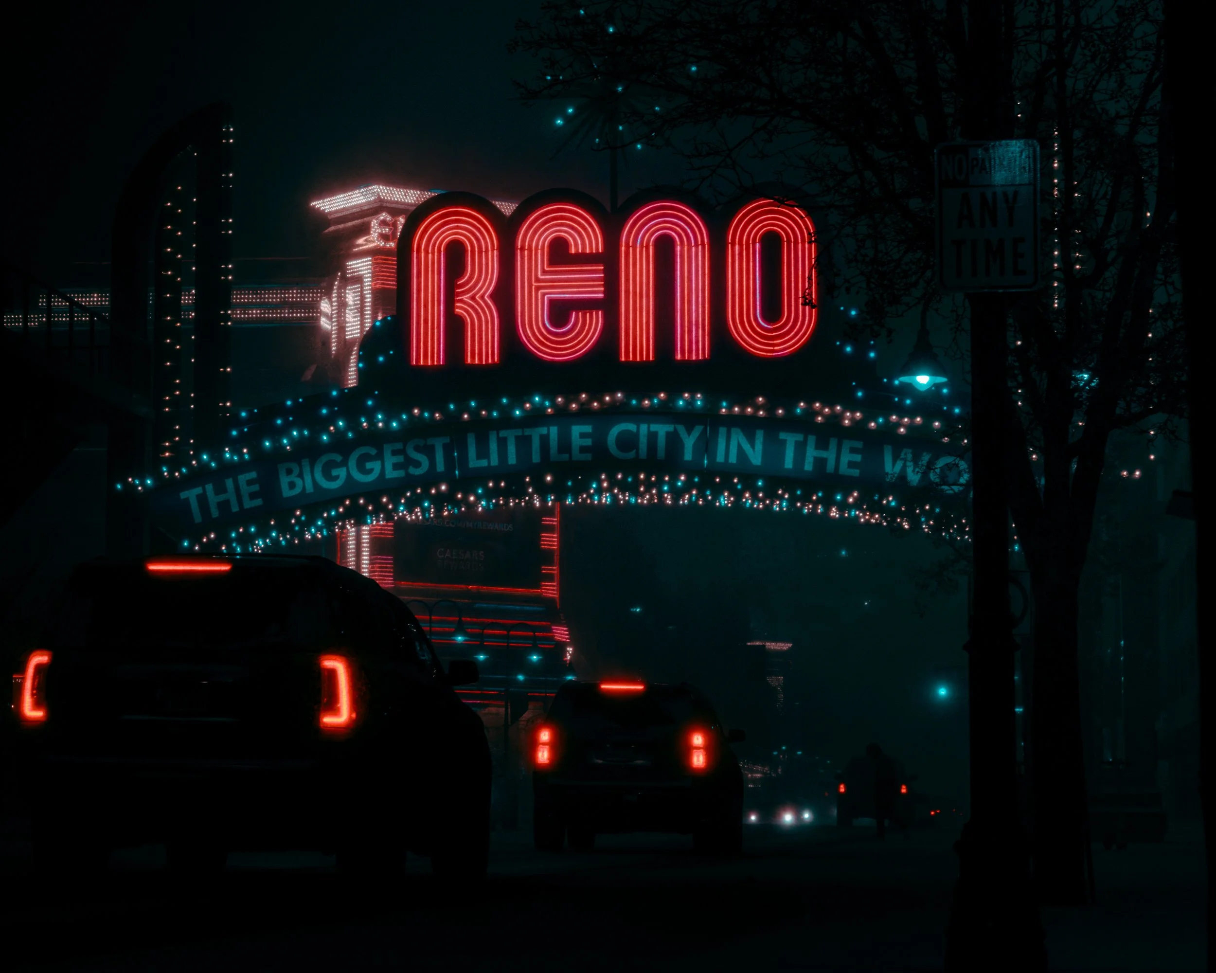 Nighttime scene of a city street with bright neonlights, including a large red neon sign that spells 'RENO'. Cars are driving on the street with their taillights glowing, and there are string lights on the trees and buildings.