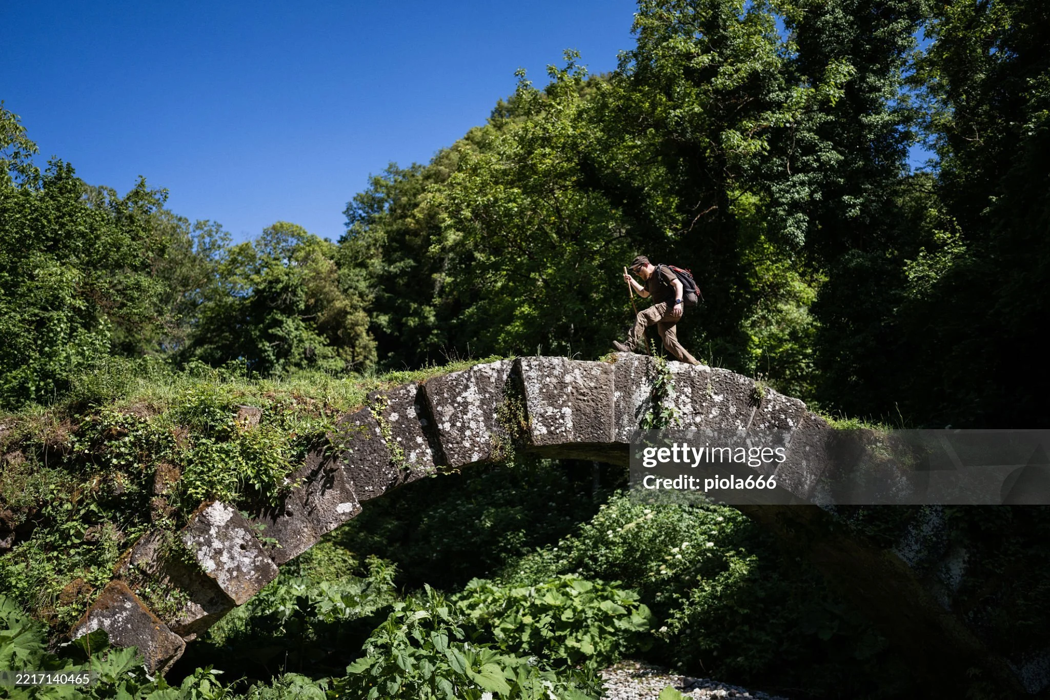 A man crossing the ruins of a Roman bridge 