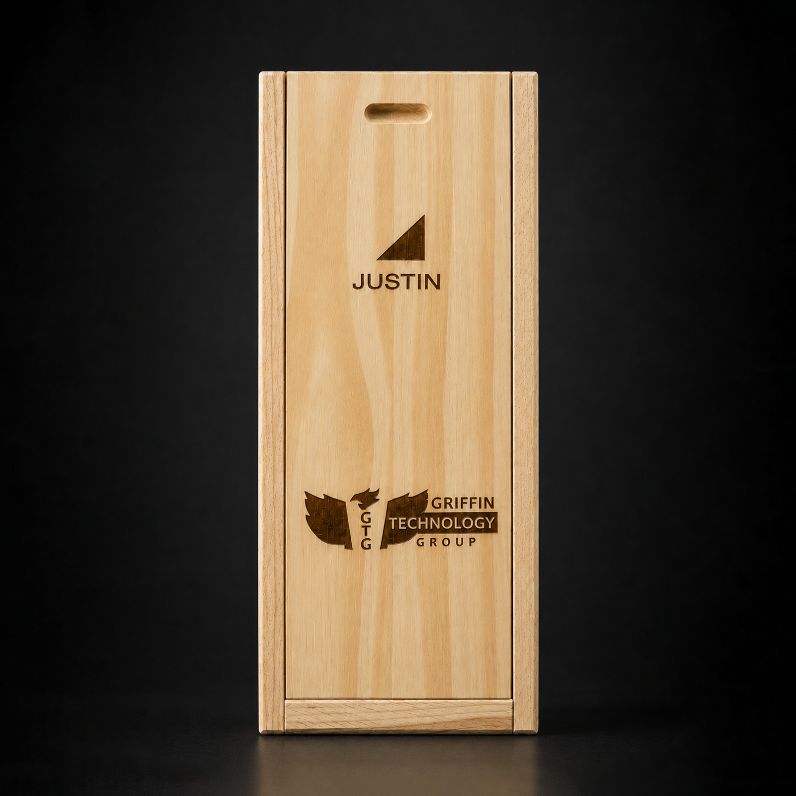 Wooden rectangular box with a front wood panel, laser-engraved with a logo featuring an upward-pointing triangle and the name 'JUSTIN' below it. The lower part of the box displays a laser-engraved logo with an eagle and text, including 'GTTG,' 'GRIFFIN,' 'TECHNOLOGY,' and 'GROUP.'