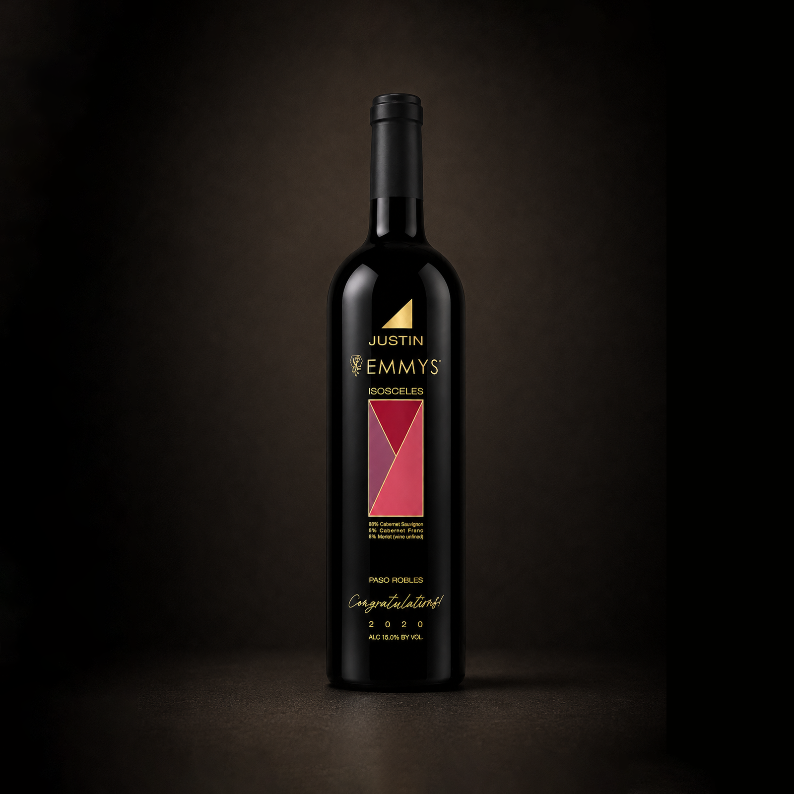 A dark bottle of Justin Emmy's Isosceles wine with a black label, gold and red geometric design, and winery details, set against a dark gradient background.