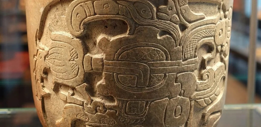 Photograph of an ancient carved stone artifact with intricate patterns and designs, possibly Mayan or Aztec.