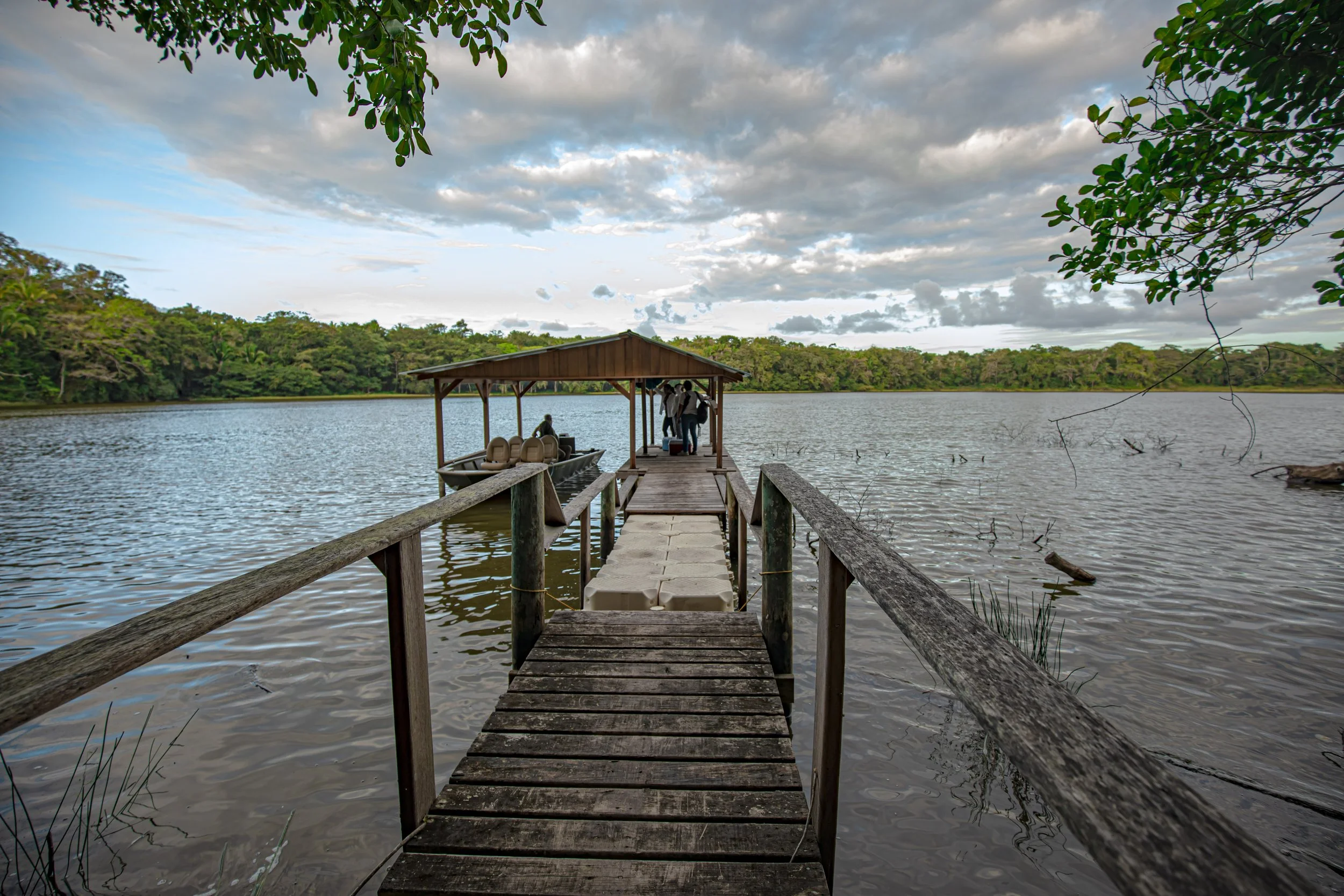 Wooden dock leading out to a roofed shelter over a calm lake
