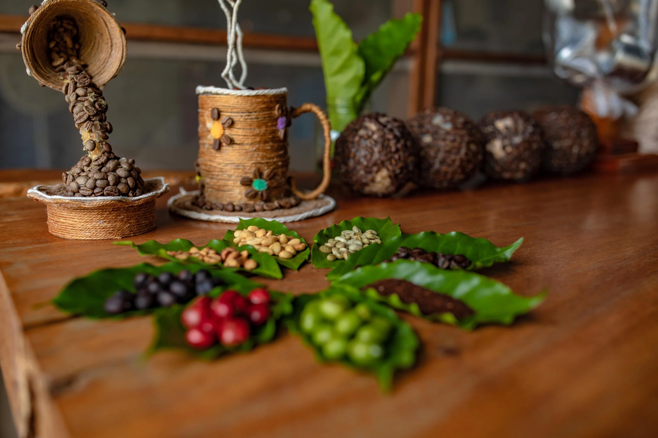 Coffee beans pouring from a cup onto a wooden table scattered with coffee cherries and leaves