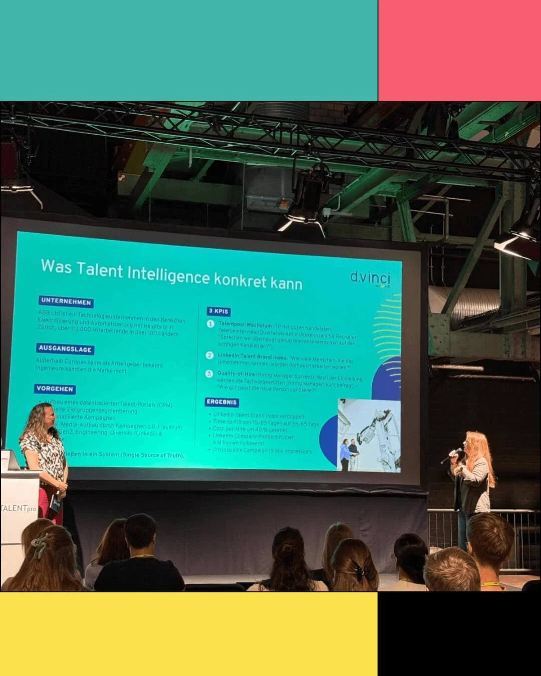 Präsentation auf einer Bühne zeigt eine Folie mit dem Titel 'Was Talent Intelligence konkret kann'. Es sitzen mehrere Menschen im Publikum, eine Frau mit langen braunen Haaren hält ein Mikrofon, eine andere Person steht am Podium. Der Hintergrund zeigt eine industrielle Decke und Beleuchtung.