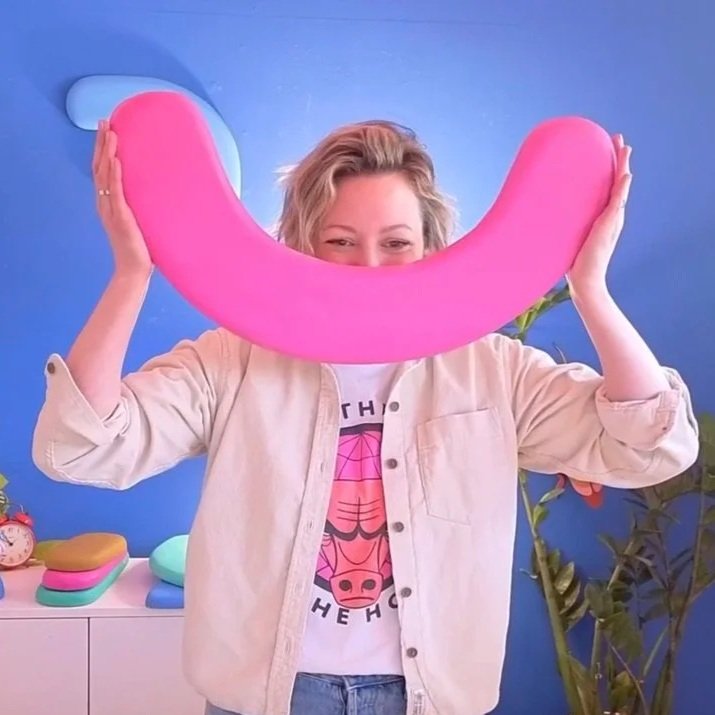 Allie holding a large pink smile shape over her face