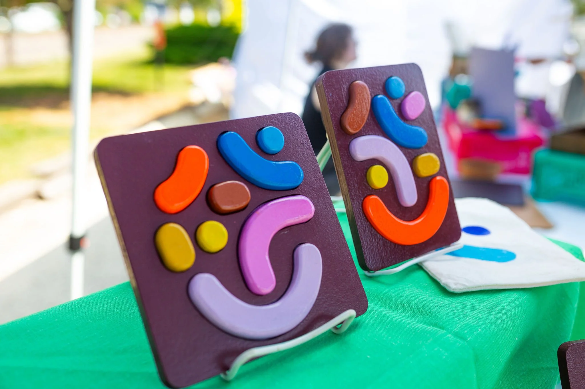 Close-up of two brown wooden boards with colorful shapes sticking to them magnetically, arranged into playful patterns.