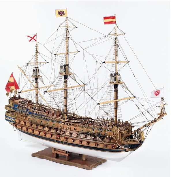 Modelo de barco pirata con banderas y detalles en velas y mástiles, hecho de madera.