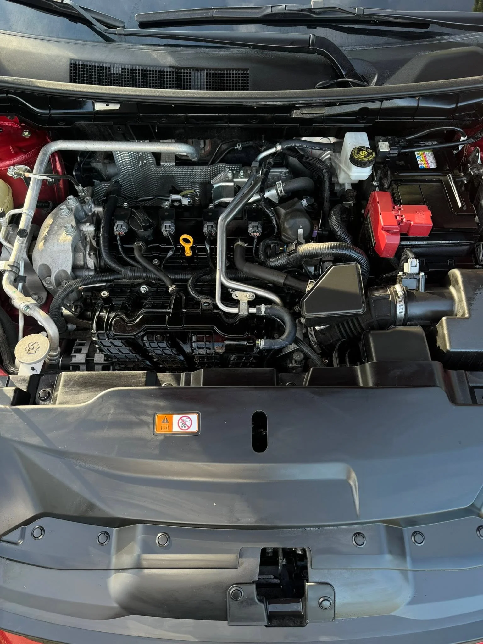 Front trunk of a car with its hood open, showing the engine compartment with various mechanical and electrical components.