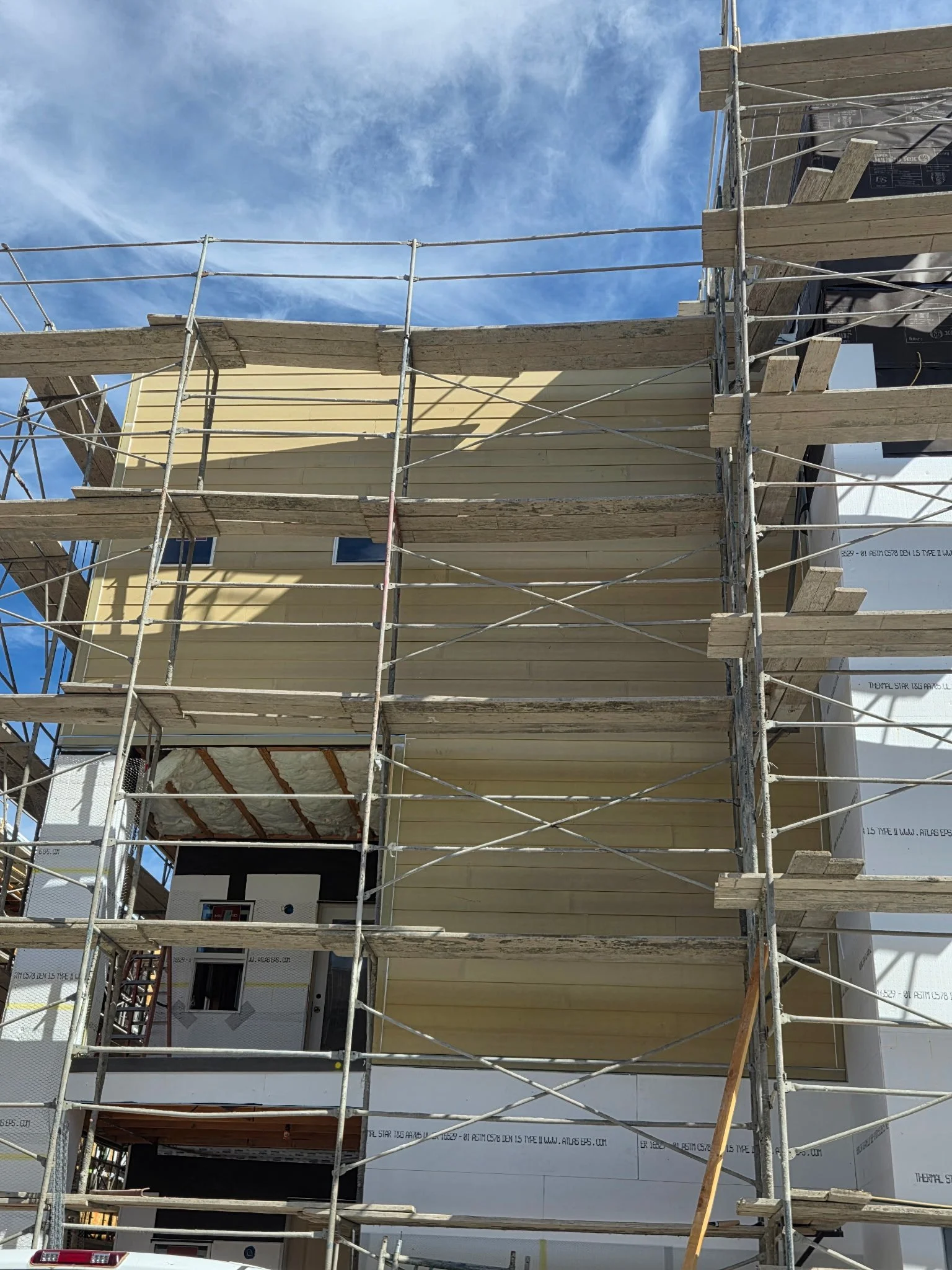 Scaffolding set up in front of a building under construction or renovation, with a clear blue sky in the background.
