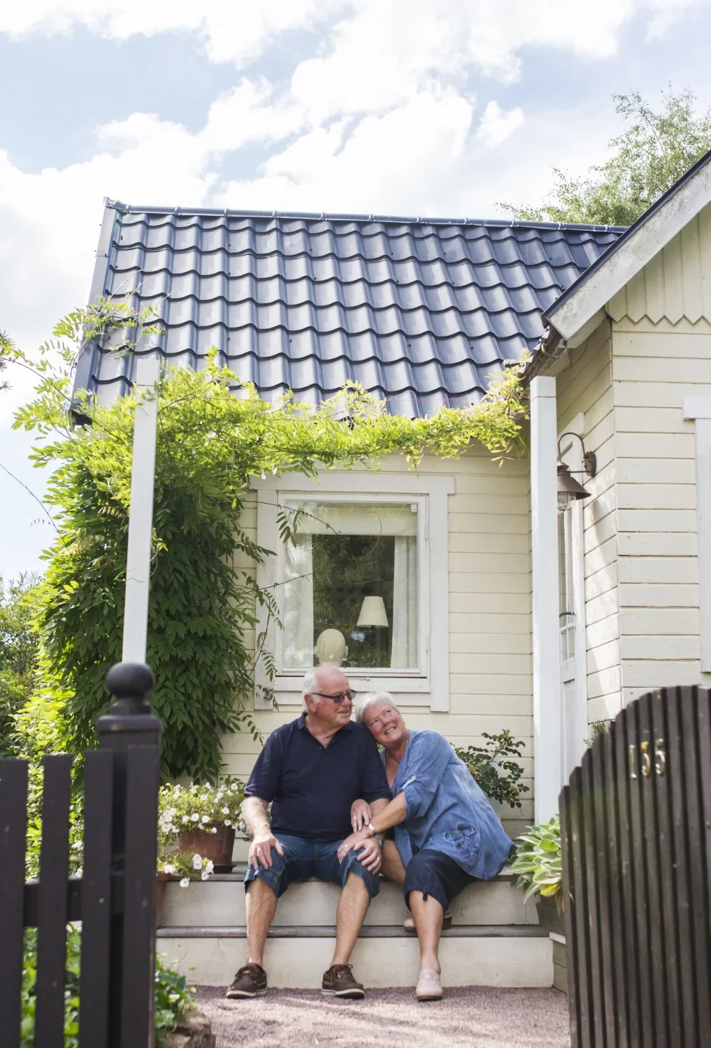 Smiling elderly couple sitting on front steps of a house