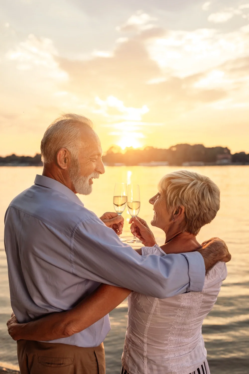 An elderly couple celebrating with champagne at sunset