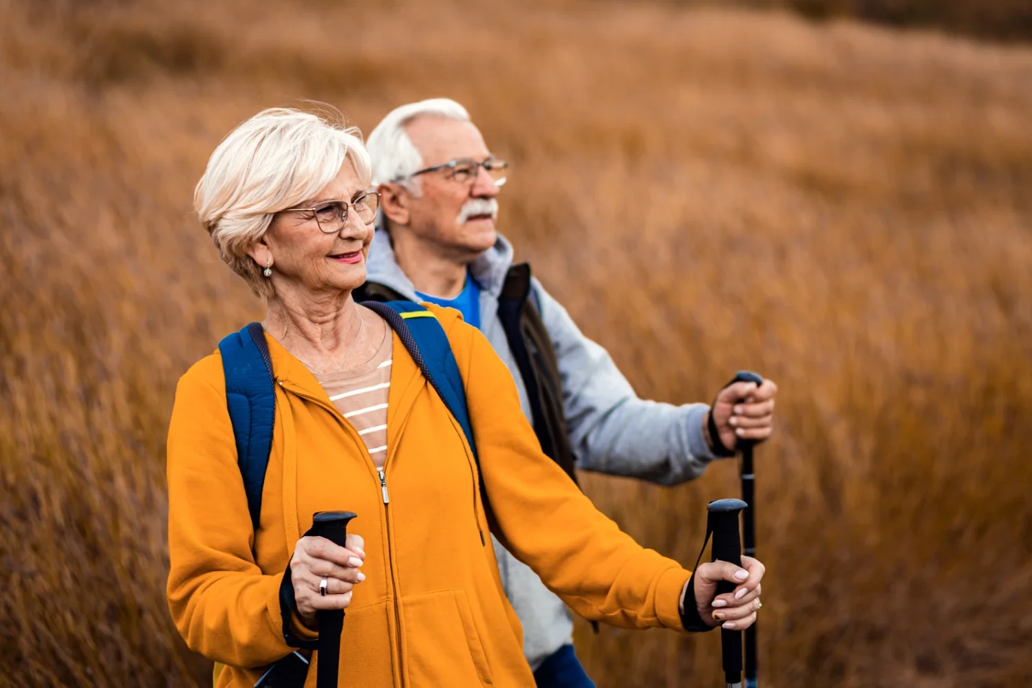An elderly couple walking through a field