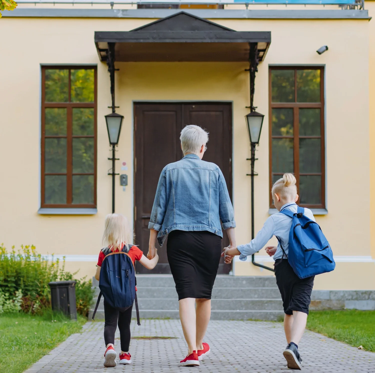A woman and two children walking towards a house