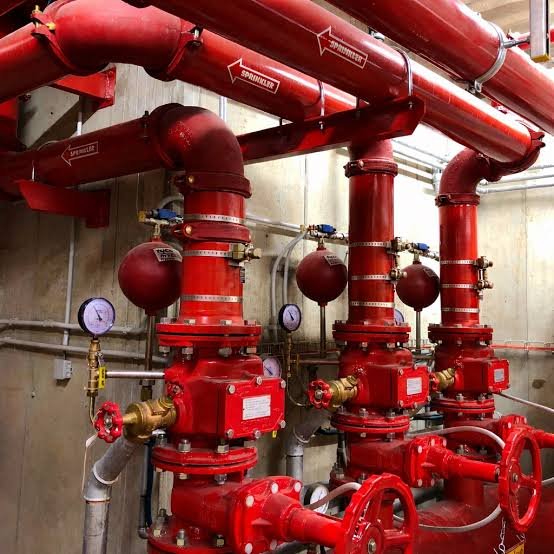 Sistema de tuberías y válvulas rojas en un cuarto de bombeo o de suministros de agua contra incendios.