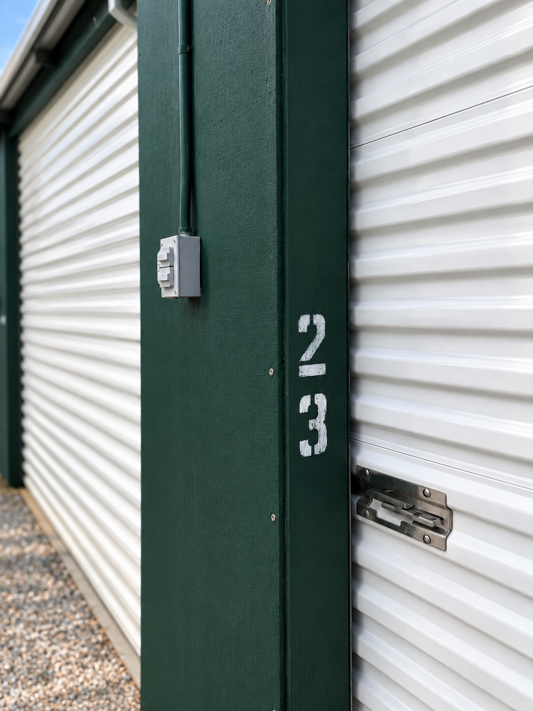 Exterior storage unit with a metal lock, and an electrical box attached to the side.