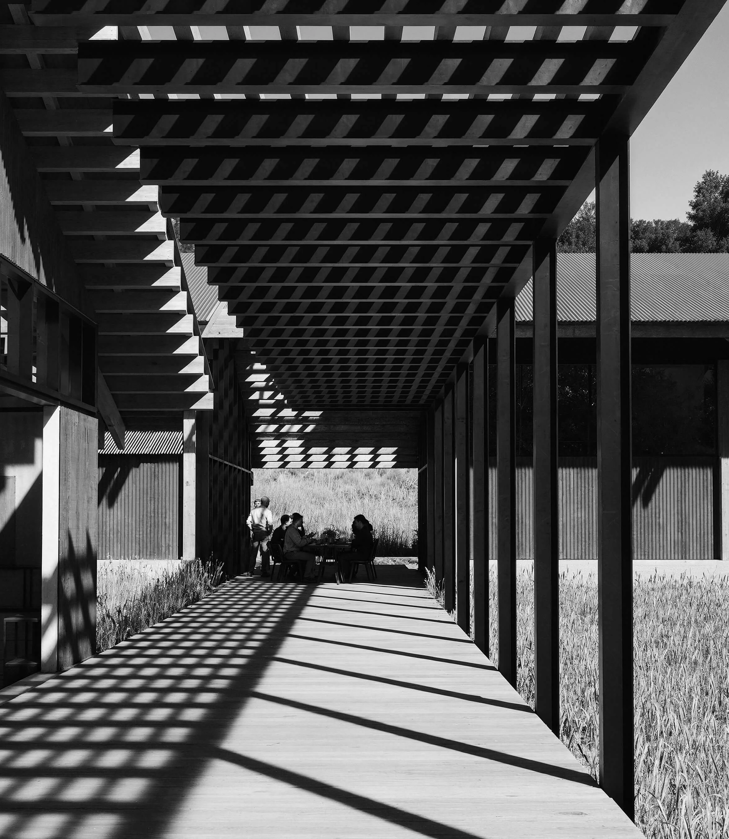 Covered outdoor walkway casting rhythmic shadows beneath the timber structure of SoCal Rancho