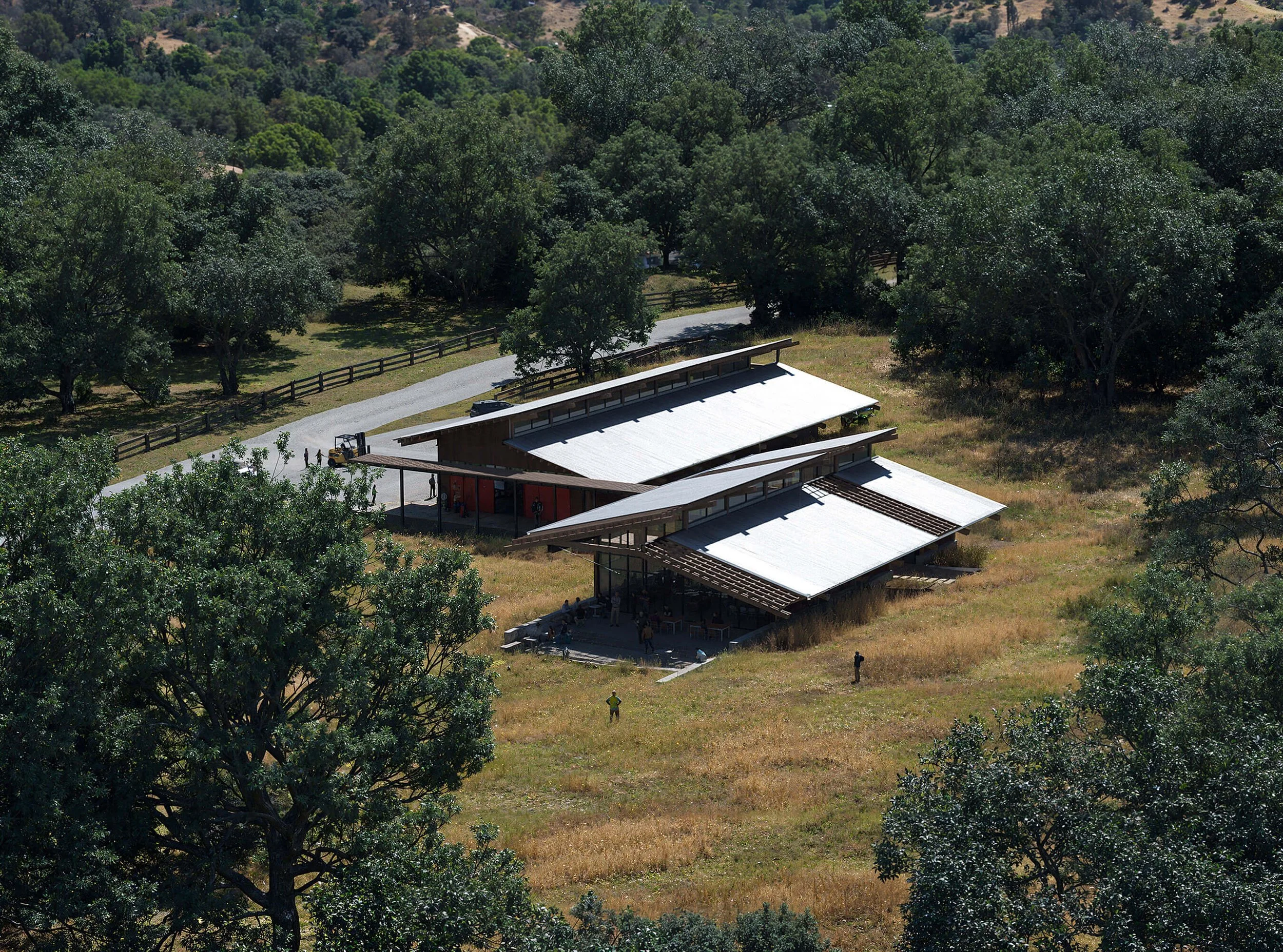 Aerial view showing the low roof forms of SoCal Rancho extending across the rural site