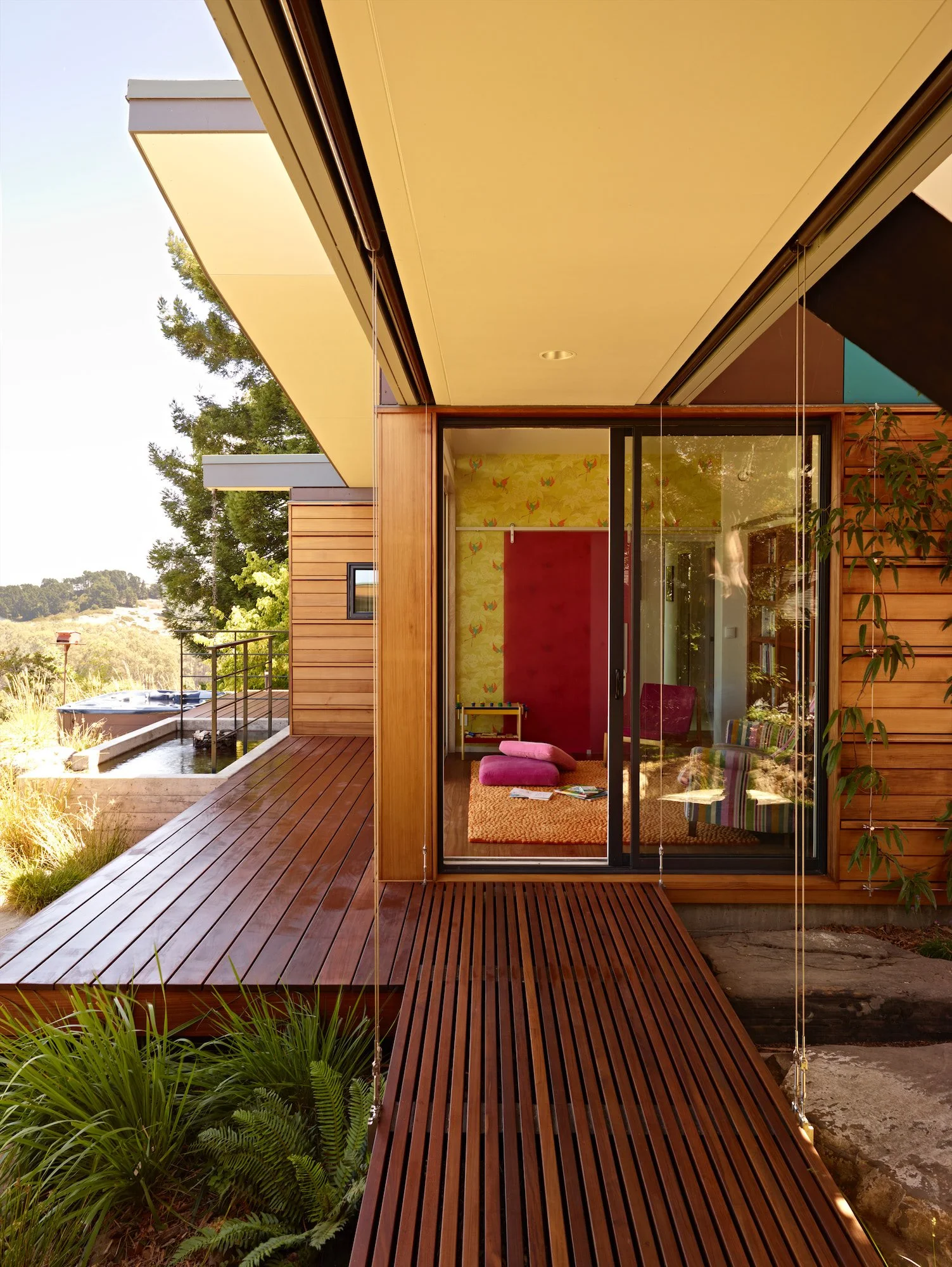 Slatted wood bridge approaching a glass-walled room at Butterfly House