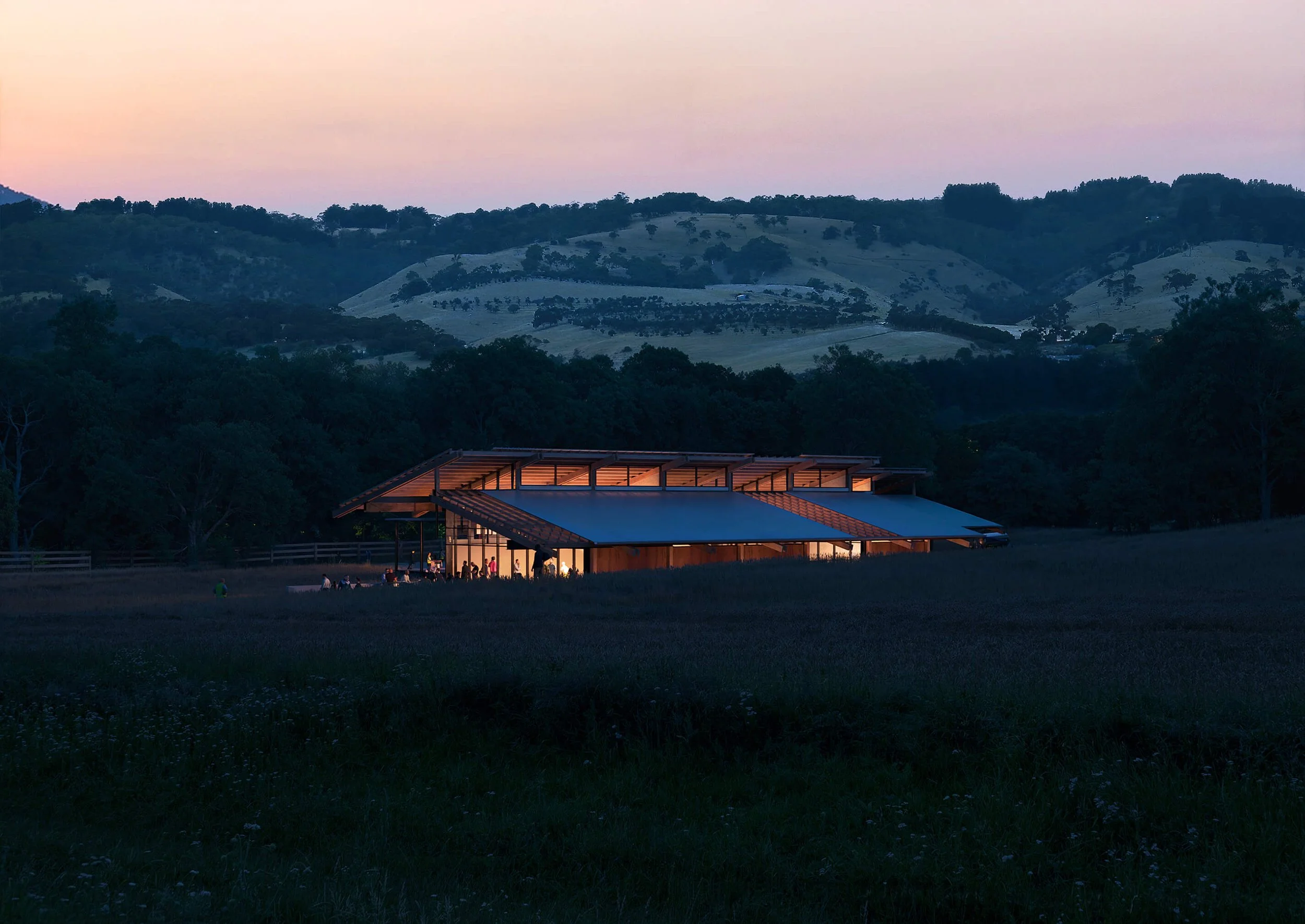 SoCal Rancho glowing at dusk beneath a broad articulated roof in the Southern California landscape