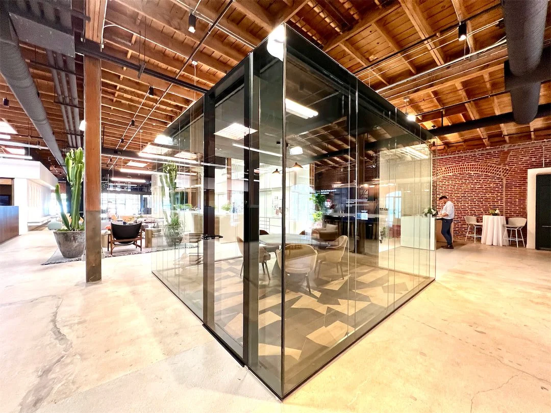 Transparent glass meeting room inserted within the historic timber-and-brick interior of Pivot Interiors