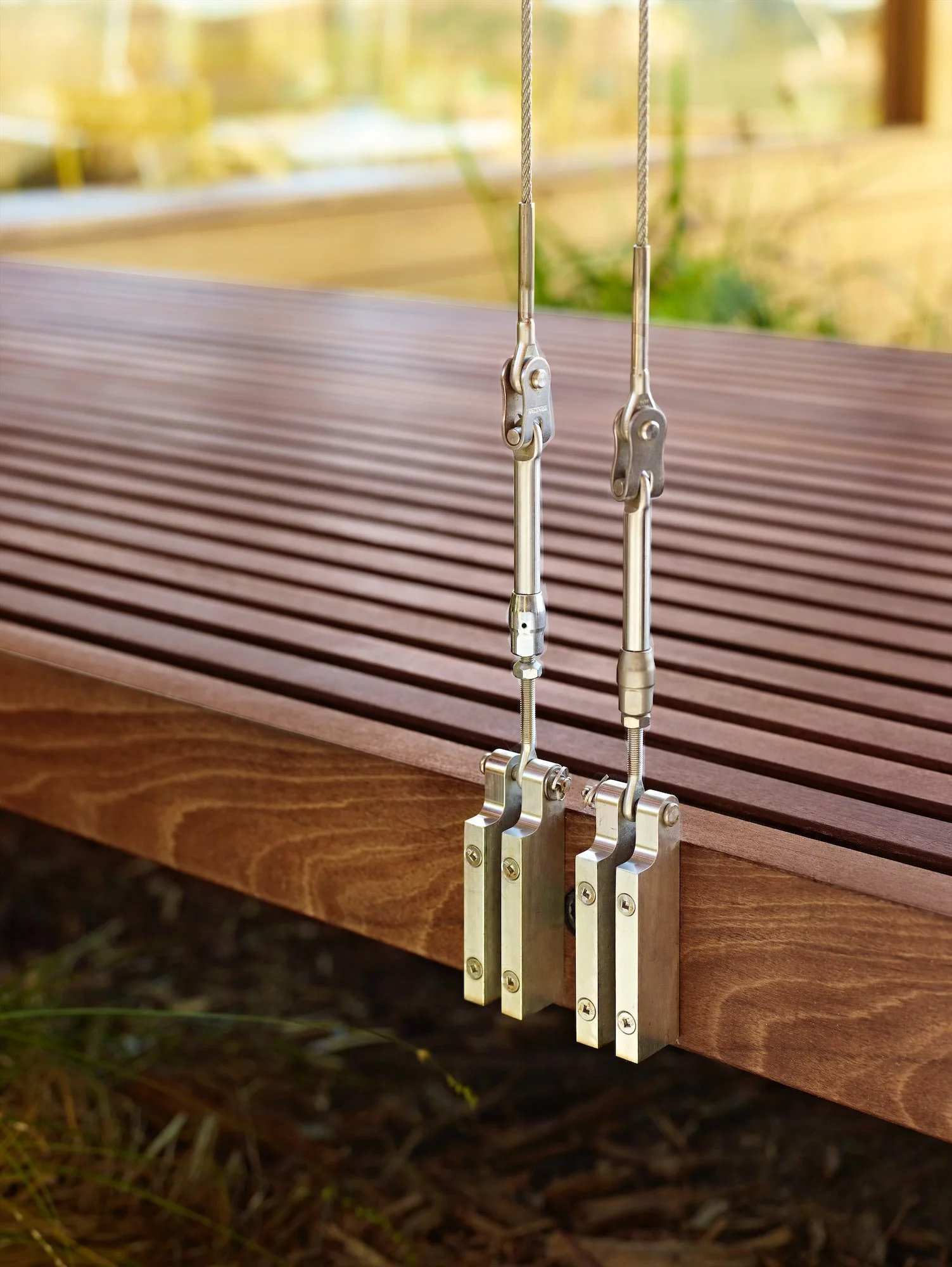 Stainless-steel cable suspension detail supporting an open-air wood bridge at Butterfly House
