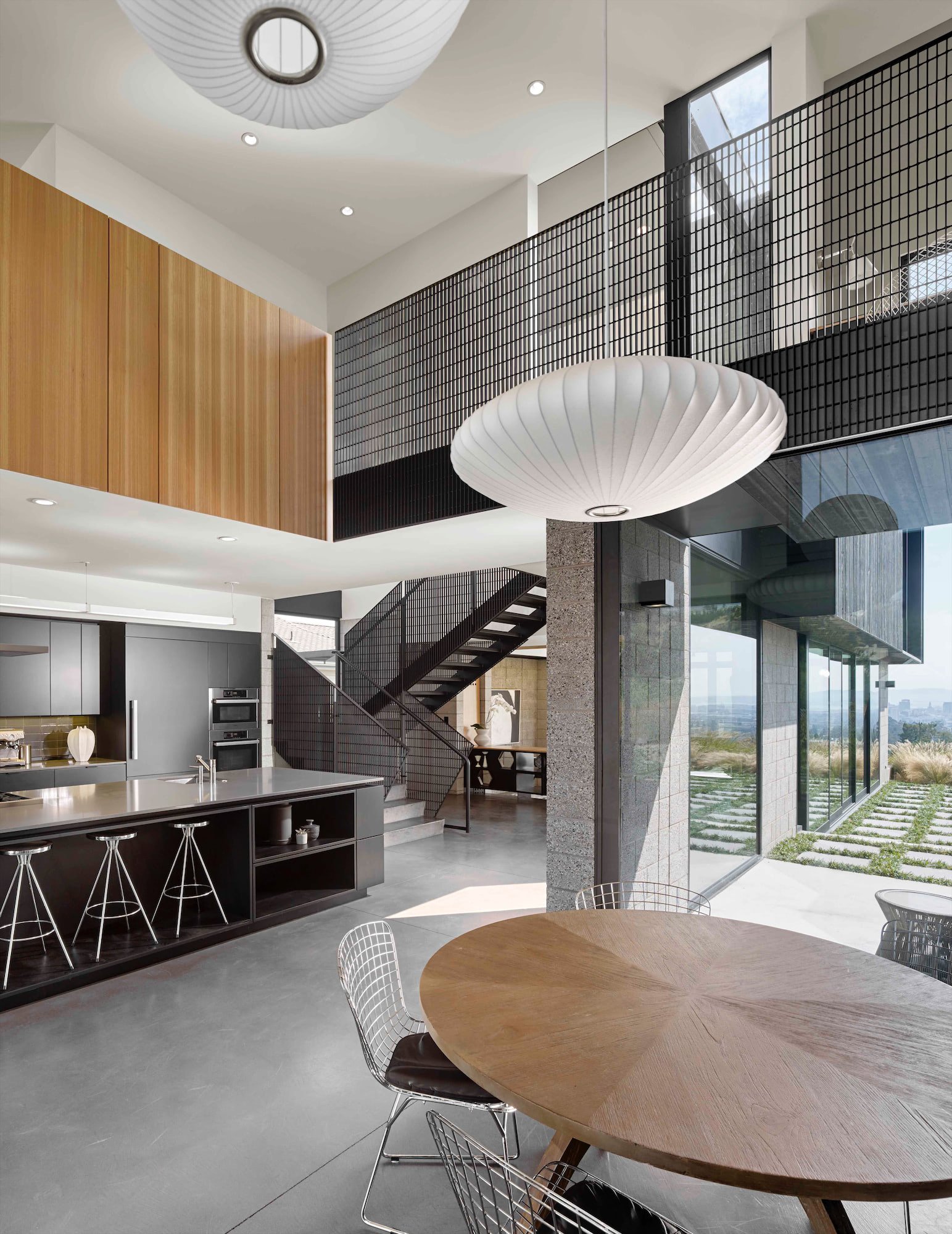 Double-height kitchen and dining space with open stair at The Phoenix residence