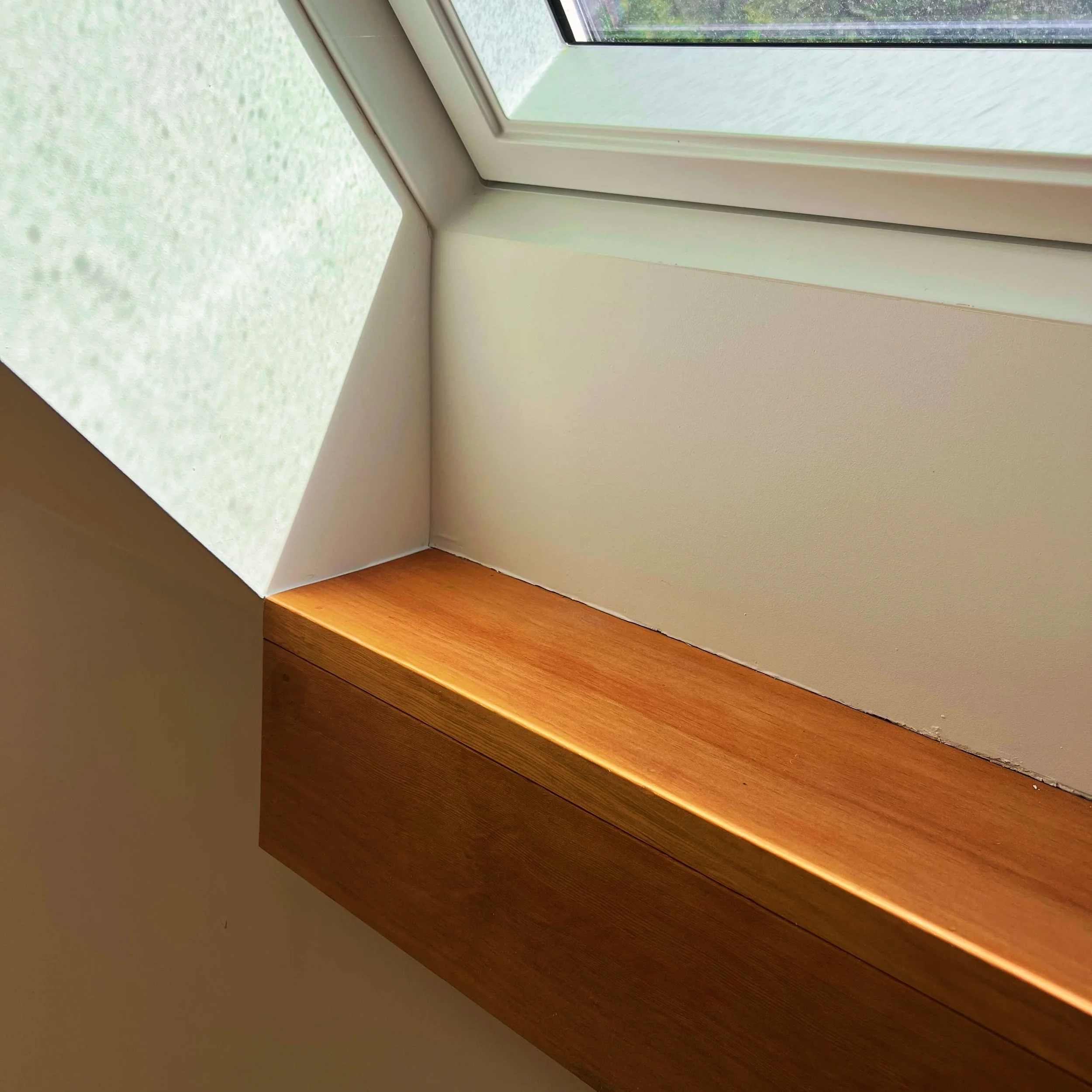 Daylight from a new skylight washing across white walls and a wood ledge