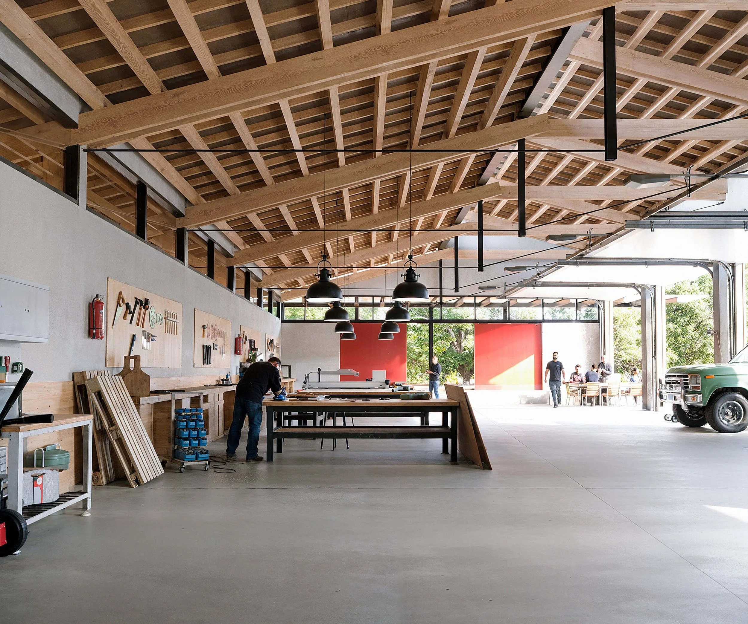 Open workshop at SoCal Rancho with timber roof structure, workbenches, and large doors to the landscape