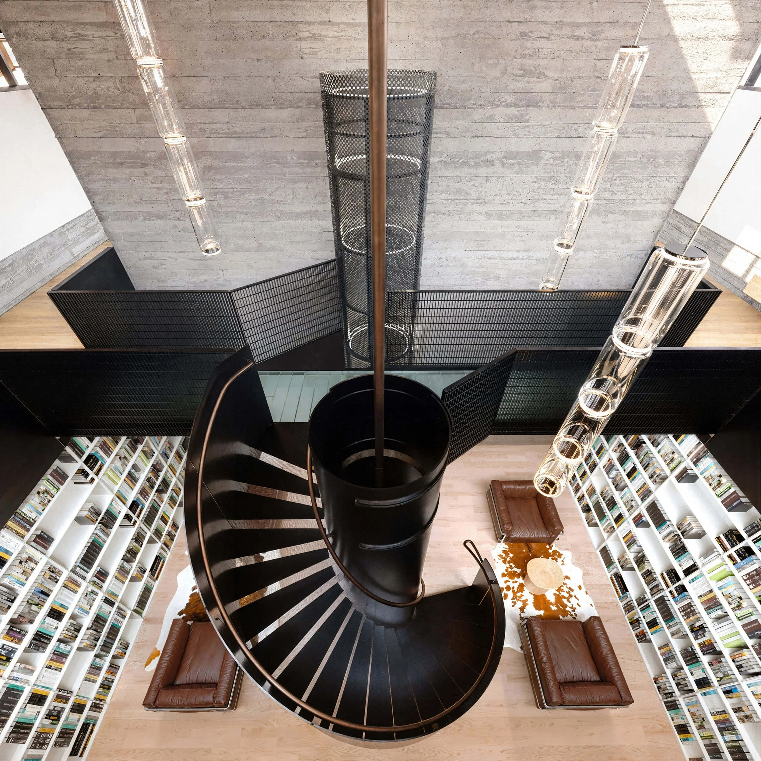 Double-height library with a black spiral stair and bridge at SoCal Rancho