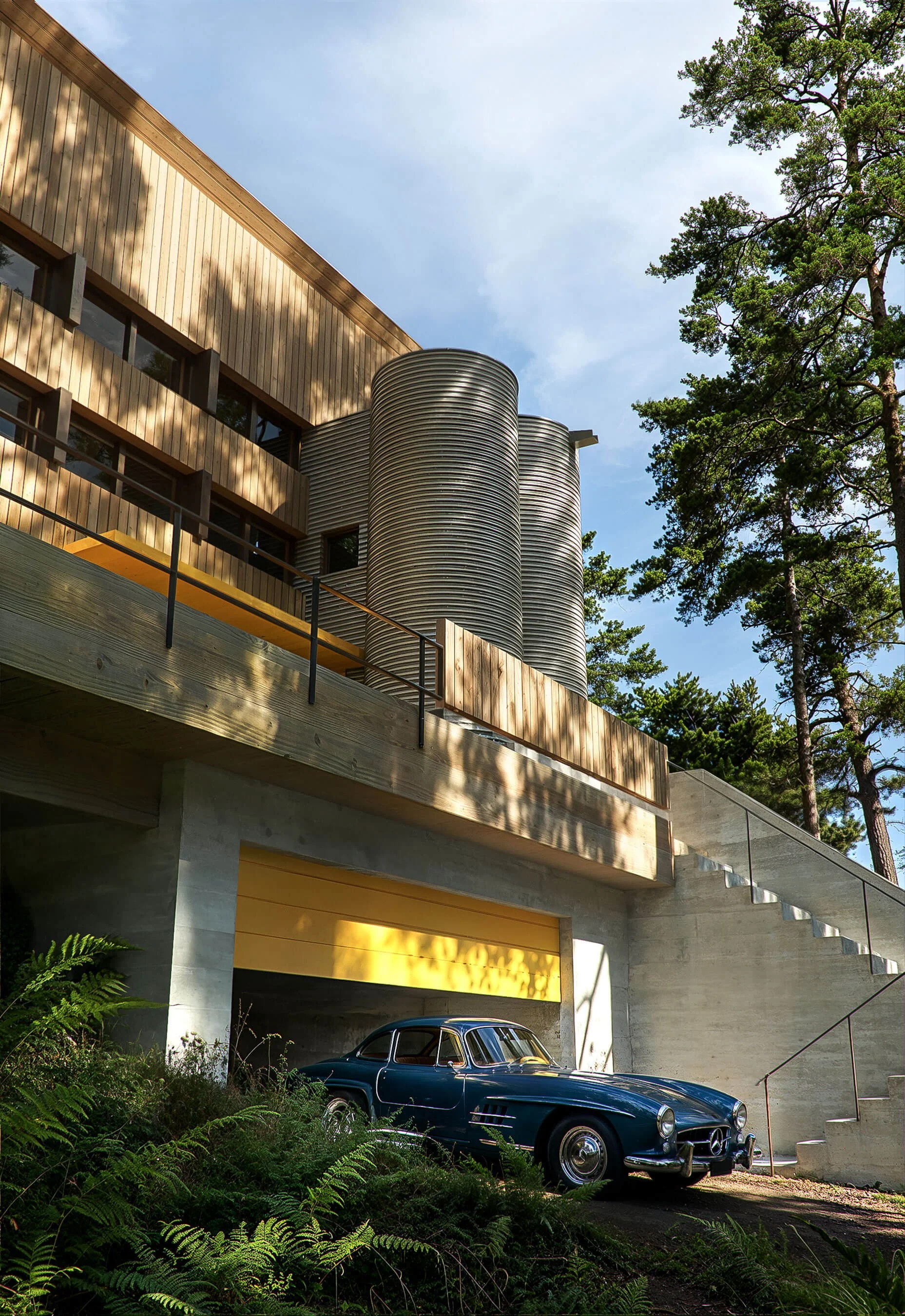 Corrugated cylindrical stair and elevator towers above the garage and entry steps of the Italic A house