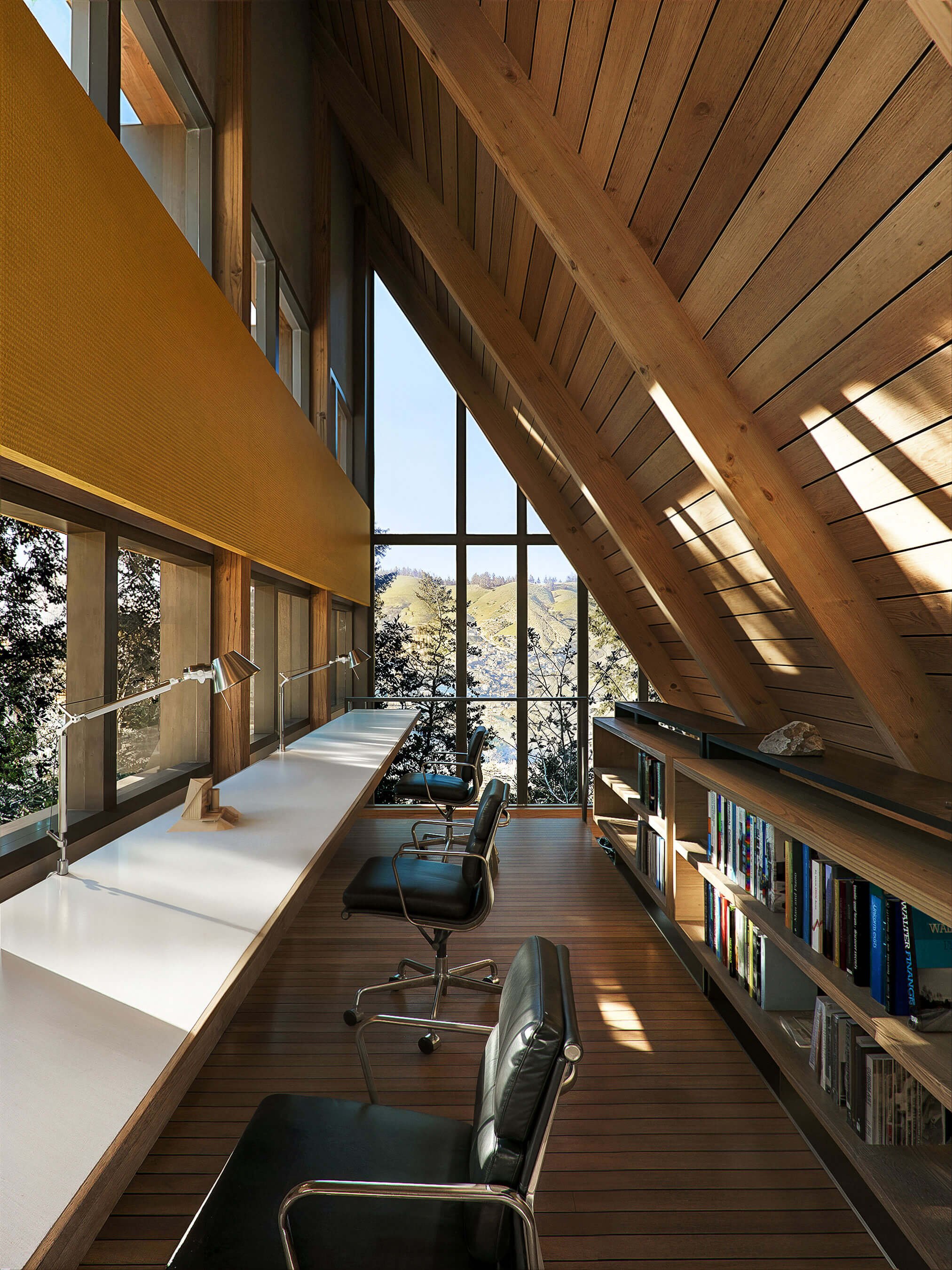 Mezzanine workspace beneath the Italic A roof with a picture window framing the valley beyond