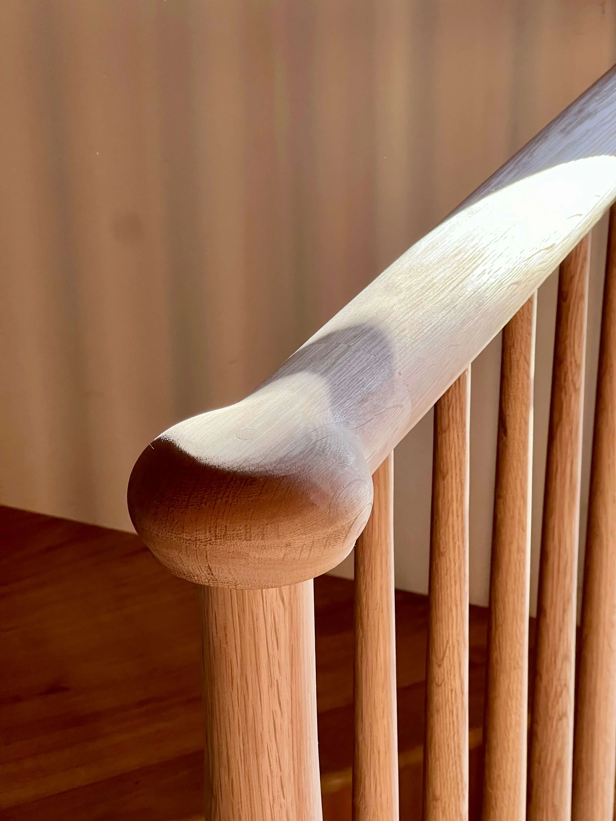 Rounded wood stair handrail and turned balusters in the restored Saltbox interior