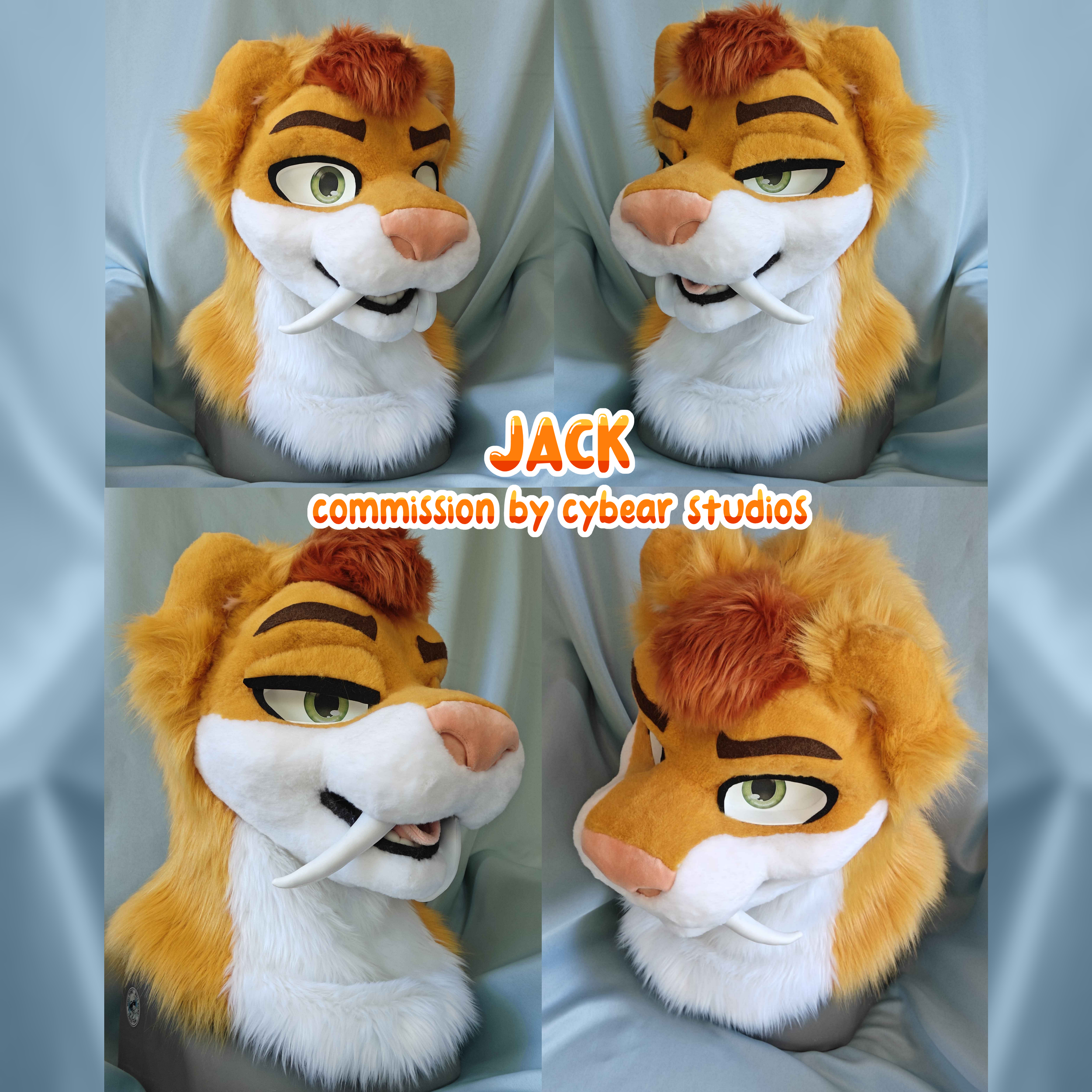 A plush lion character with green eyes, orange fur, and a white mane, sitting on a light blue fabric background. Text on the image reads 'JACK' and 'commission by cyber studios' in orange and white font.