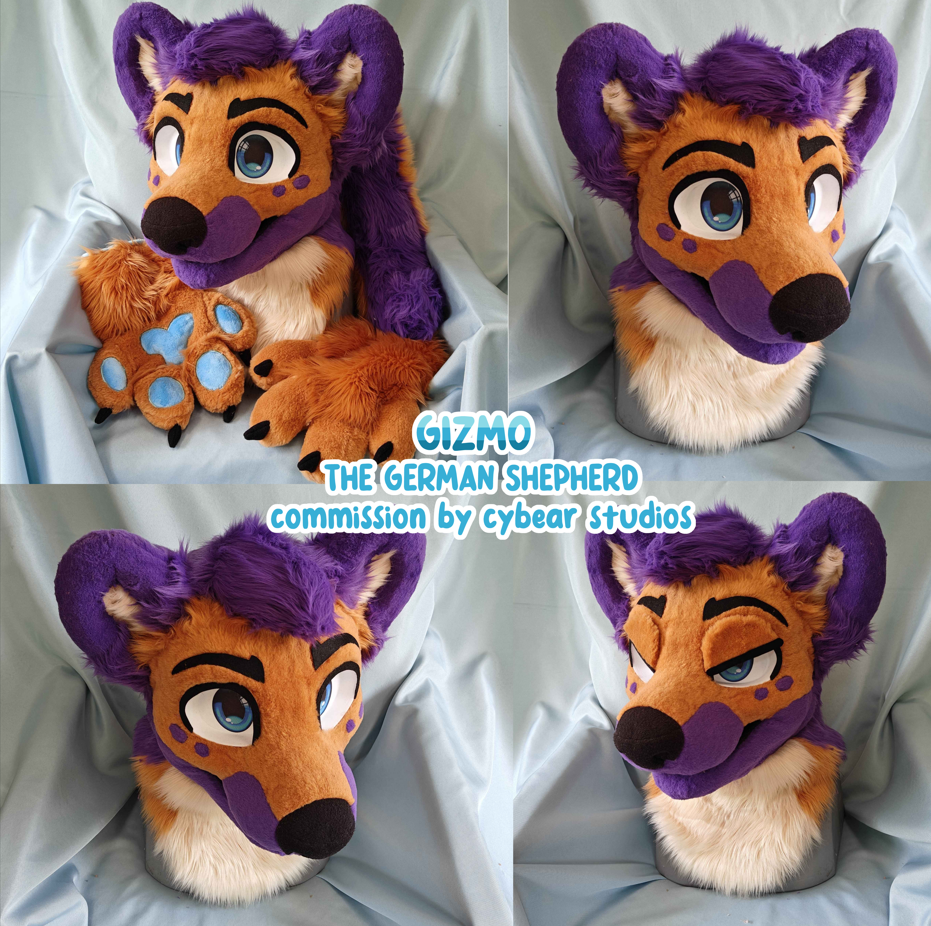 A purple, orange, and white German Shepherd fursuit head plush with large blue eyes, black eyebrows, and a friendly expression, shown from different angles on a light blue cloth background.