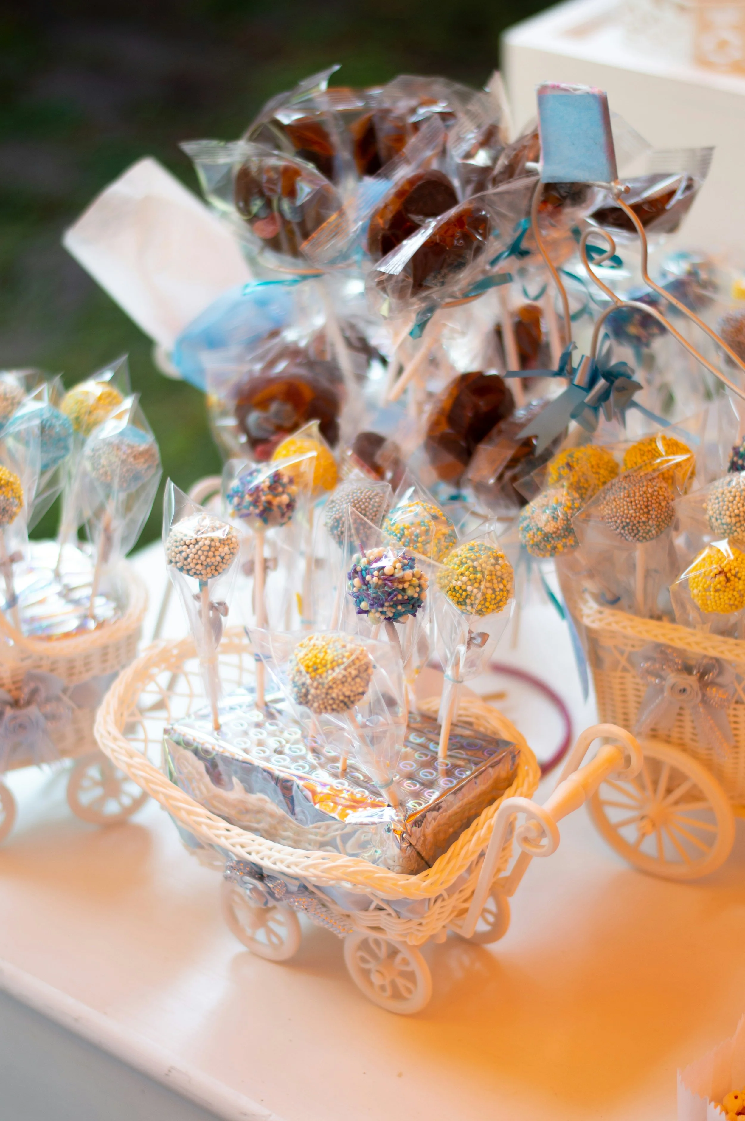 Miniature white tricycle filled with decorated cake pops and candies in a basket.