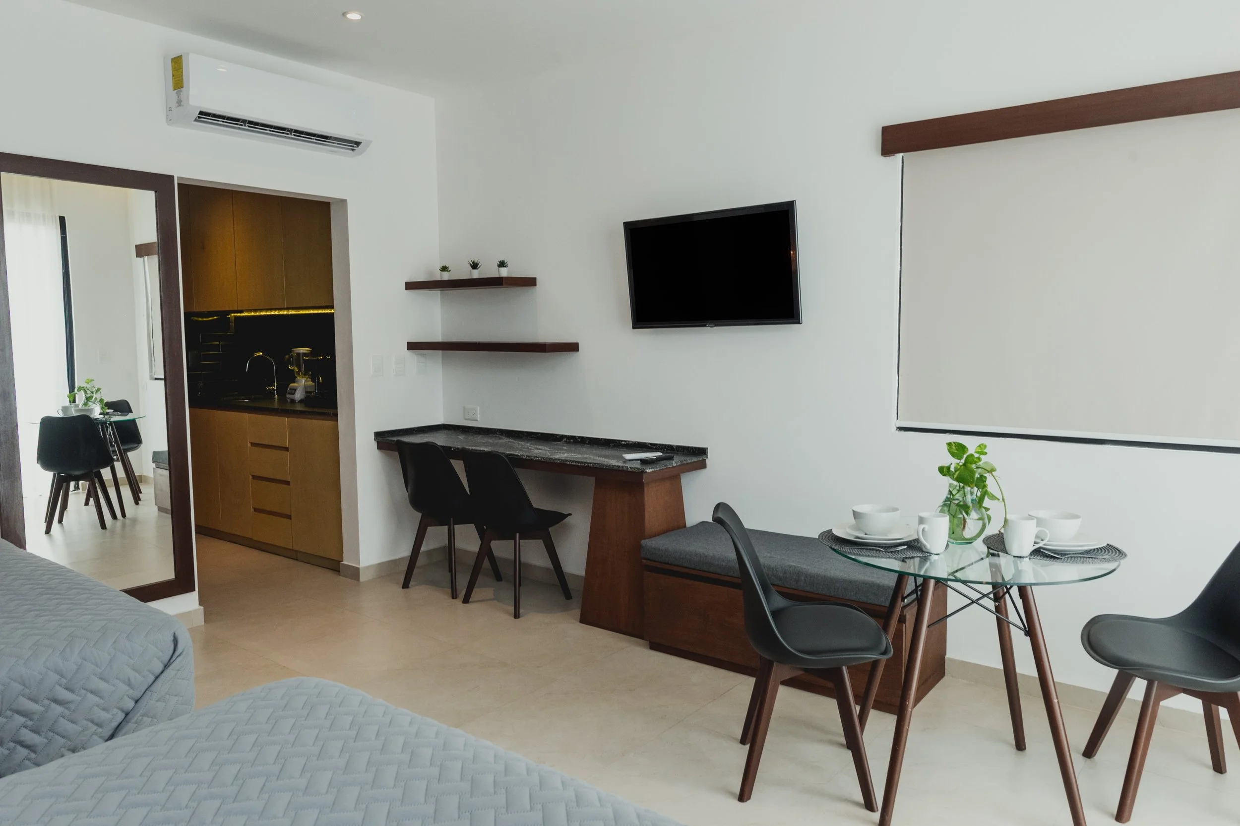 Interior de sala y comedor con mesa y sillas, televisión y aire acondicionado.