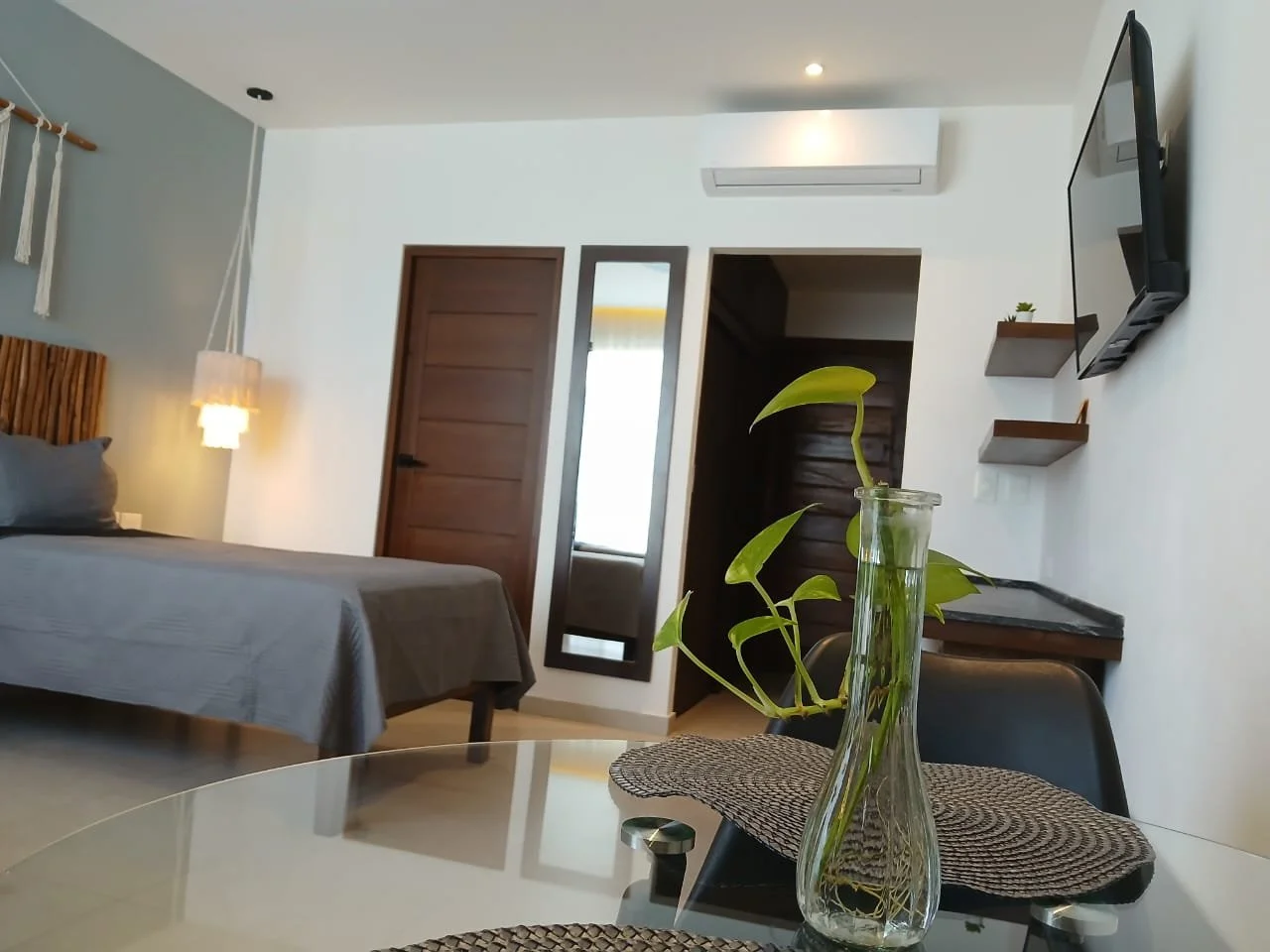 Habitación moderna con 2 camas individuales, espejo de cuerpo entero, comedor con plantas locales, tv smart, wifi, escritorio, banca y balcón.