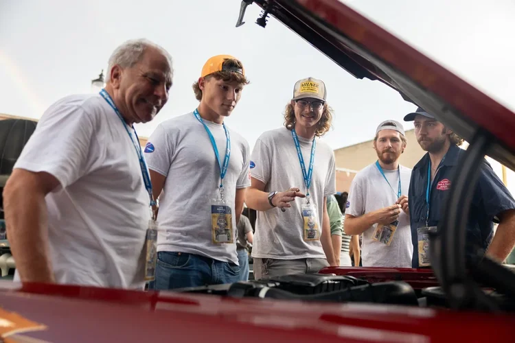 X-Cup students and mentors working together around a vintage car