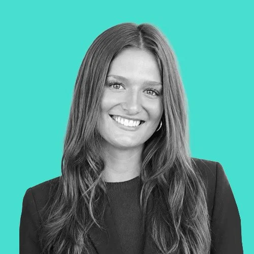 A woman with long hair smiling against a teal background.
