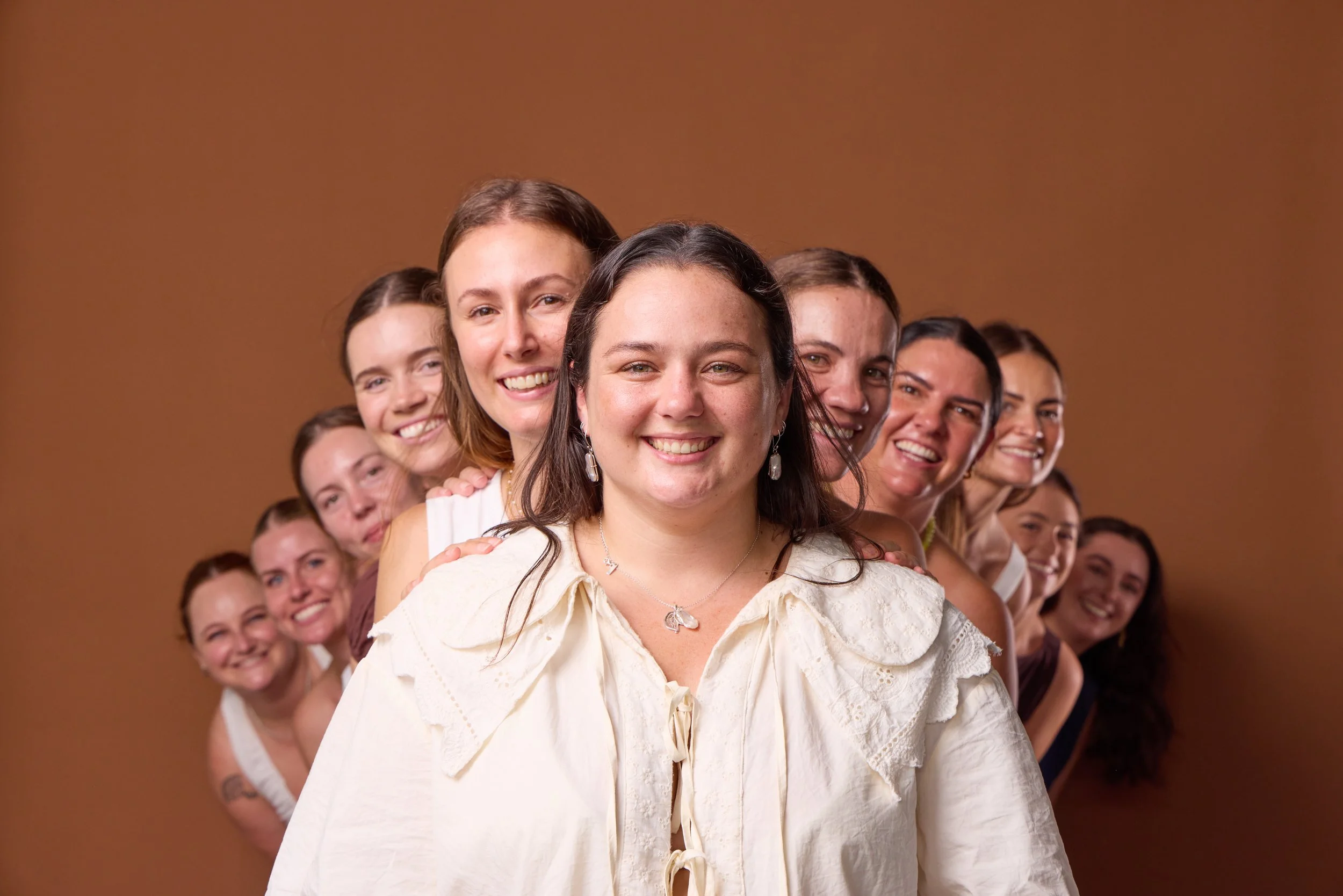 Group portrait of women photographed against a brown studio backdrop by G Studios