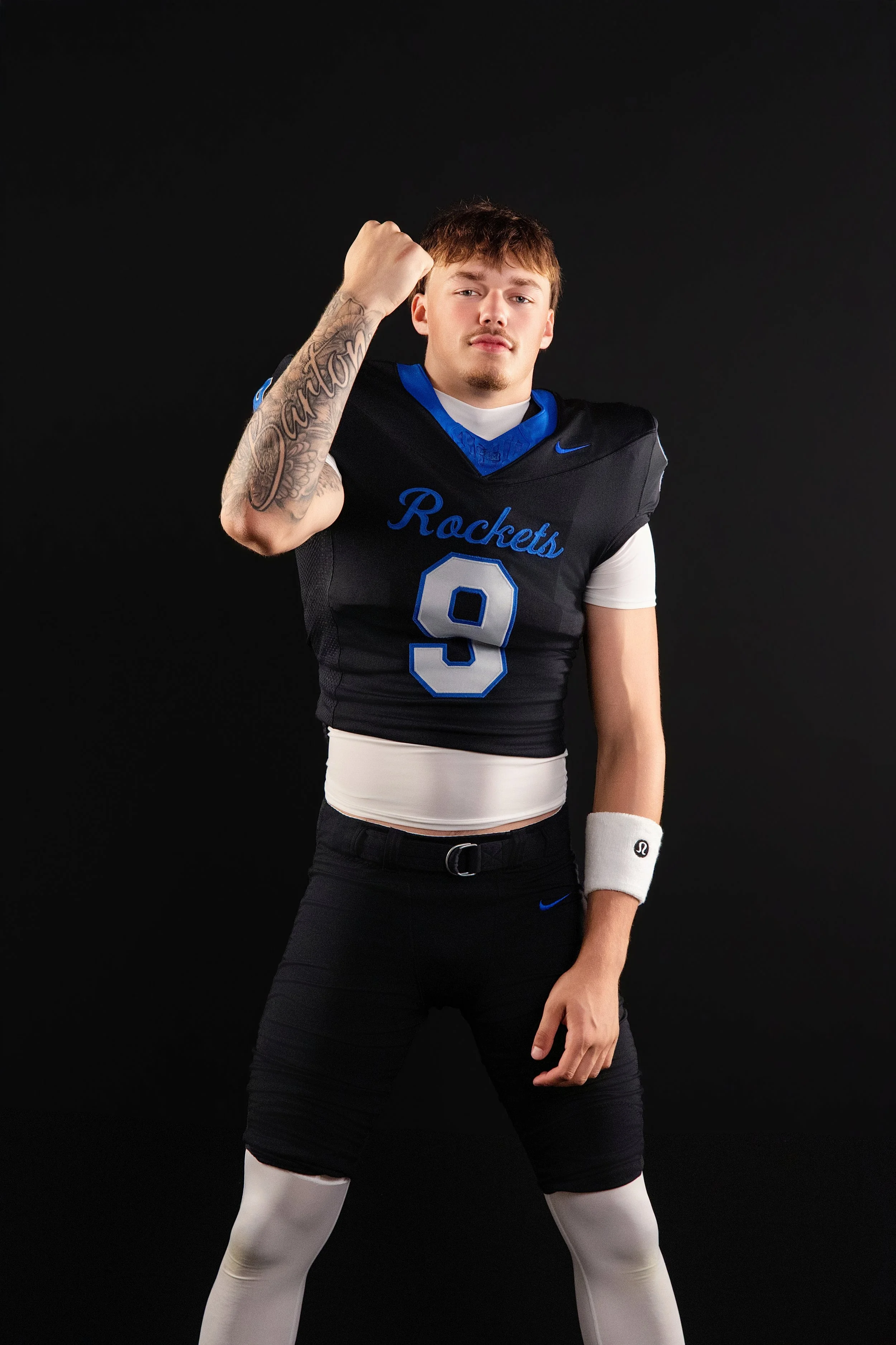 Football player wearing a black Rockets jersey with the number 9, flexing his right arm in front of a black background.