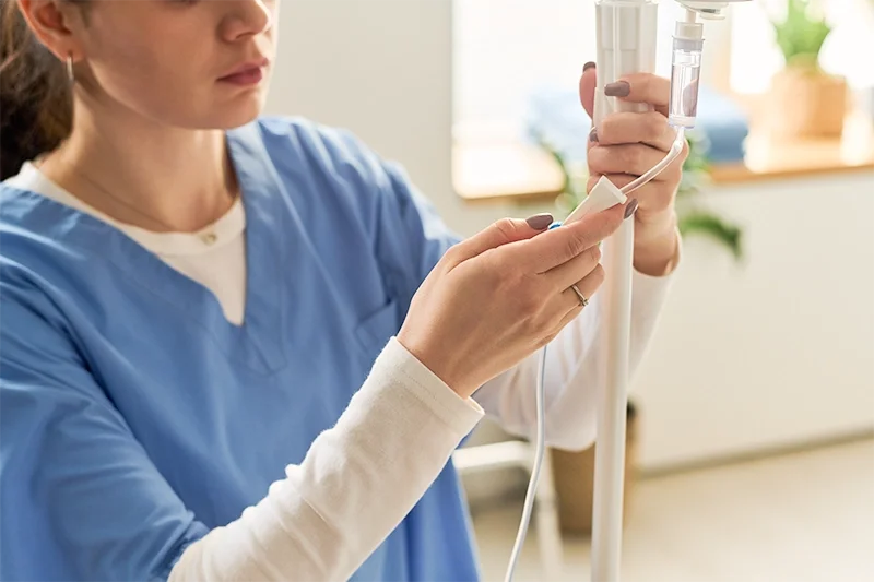A healthcare worker in blue scrubs preparing an IV drip at Redding walk in clinic for families at Integrity Medical Center
