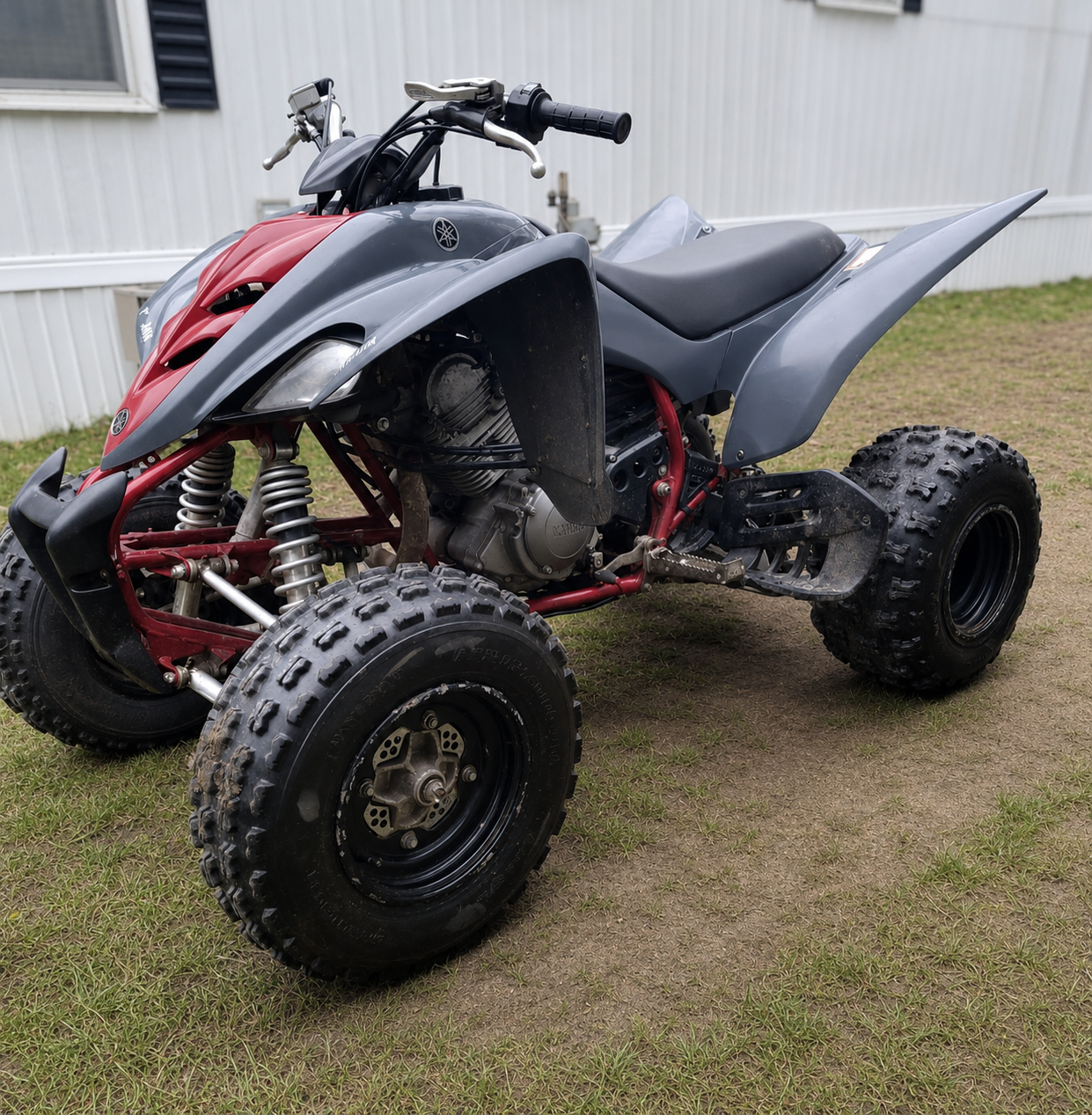 A Yamaha all-terrain vehicle (ATV) parked on grass near a white building.