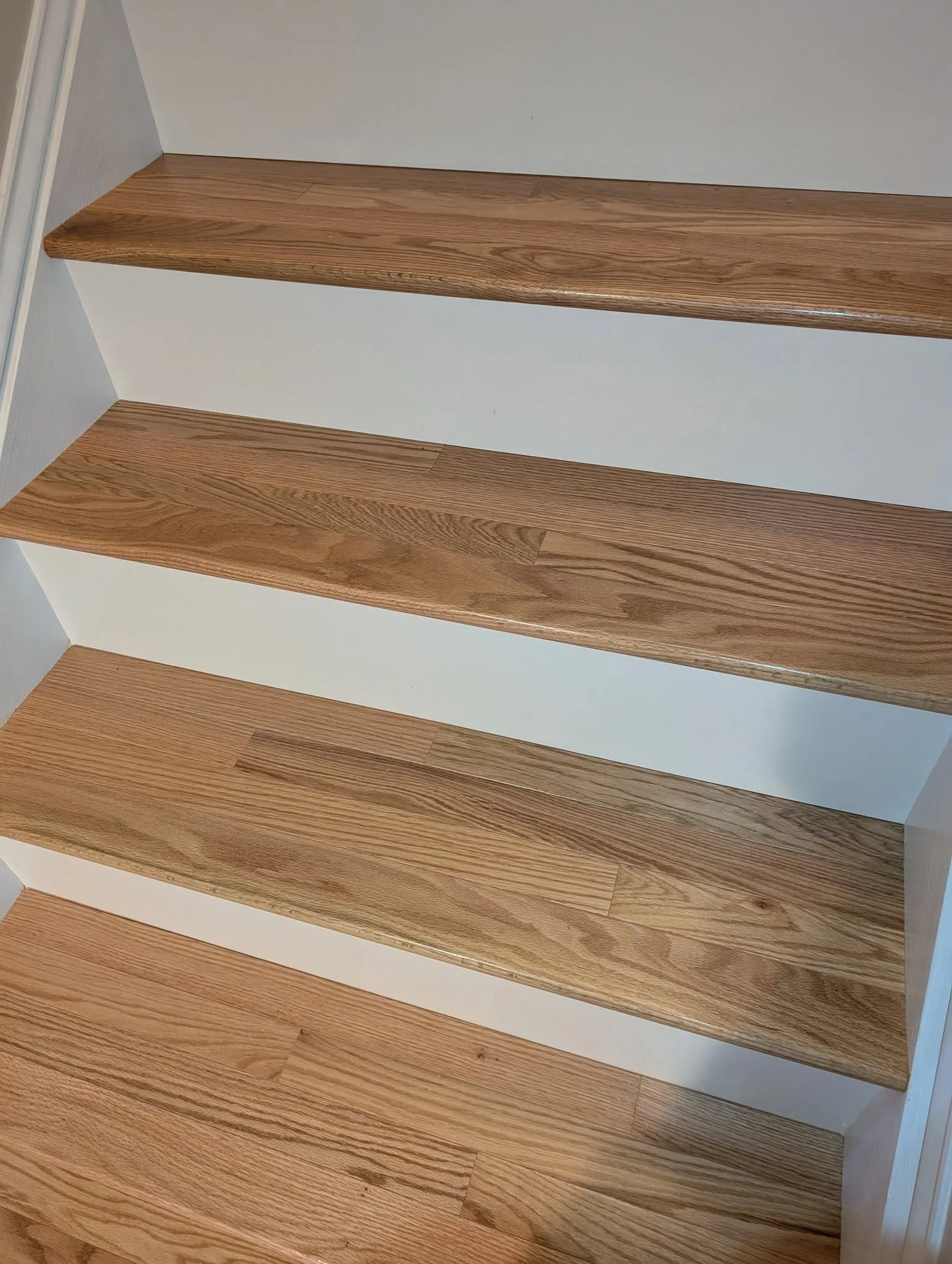 A close-up view of wooden stair treads with a natural finish and white risers.