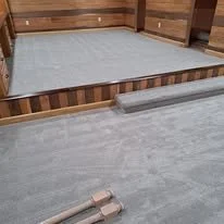 A partially assembled wooden bed frame with a mattress and some tools on the floor of a room.