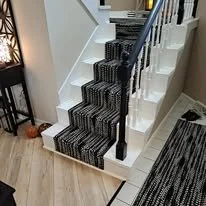 Black and white patterned staircase runner with black handrails in a modern home interior.