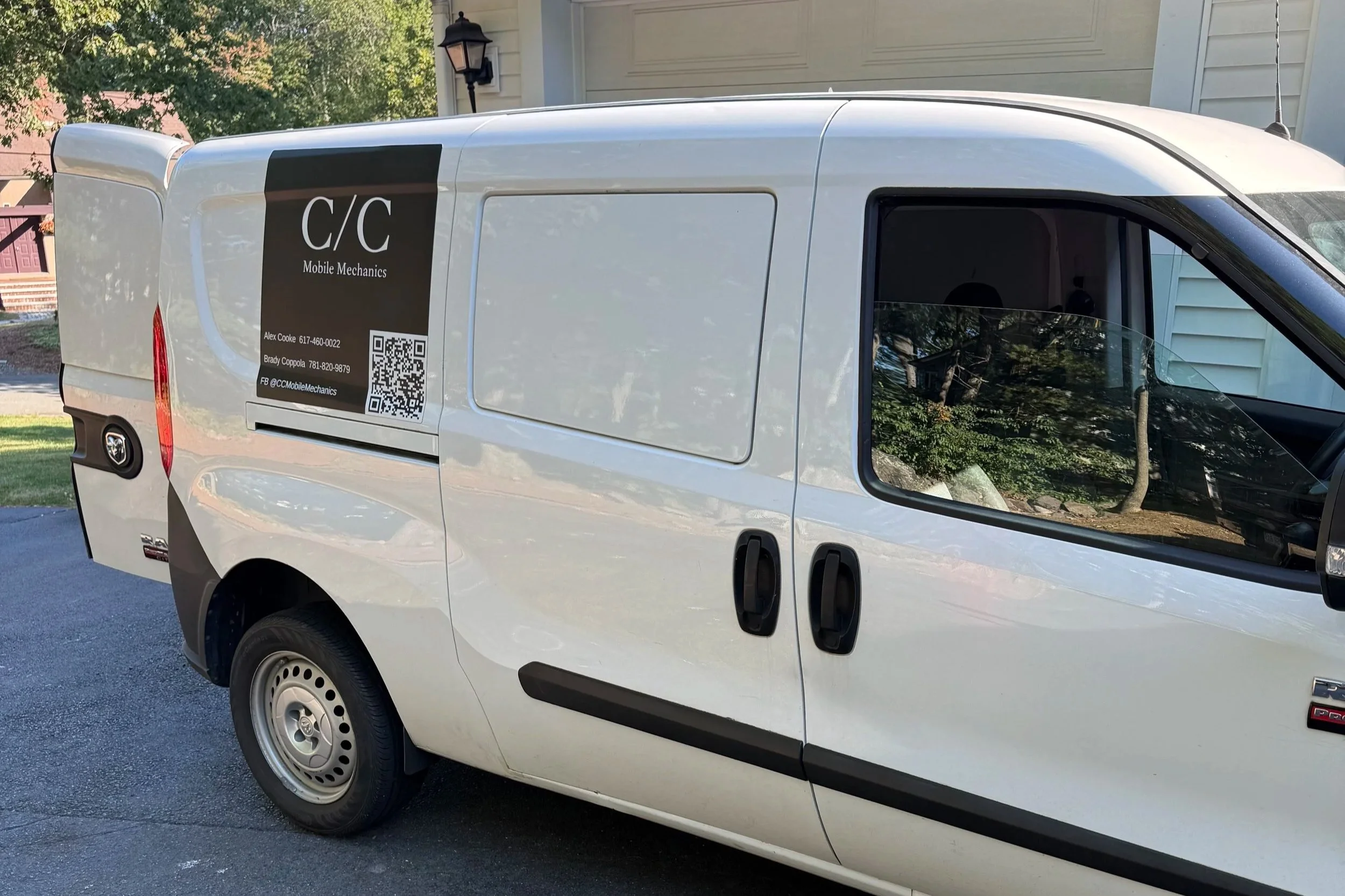 A white commercial van parked outside a house with trees in the background. The van has a black and brown logo on the side that reads 'C/C Mobile Mechanics' with contact information and a QR code.