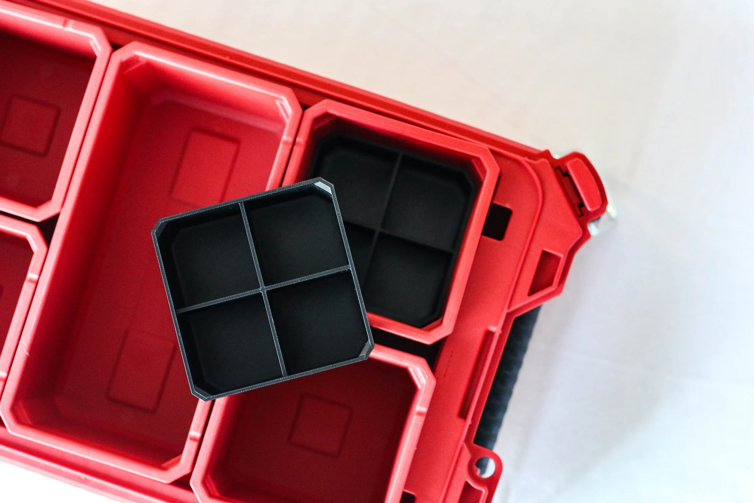 Close-up of empty red plastic storage bins with black dividers on a gray surface.